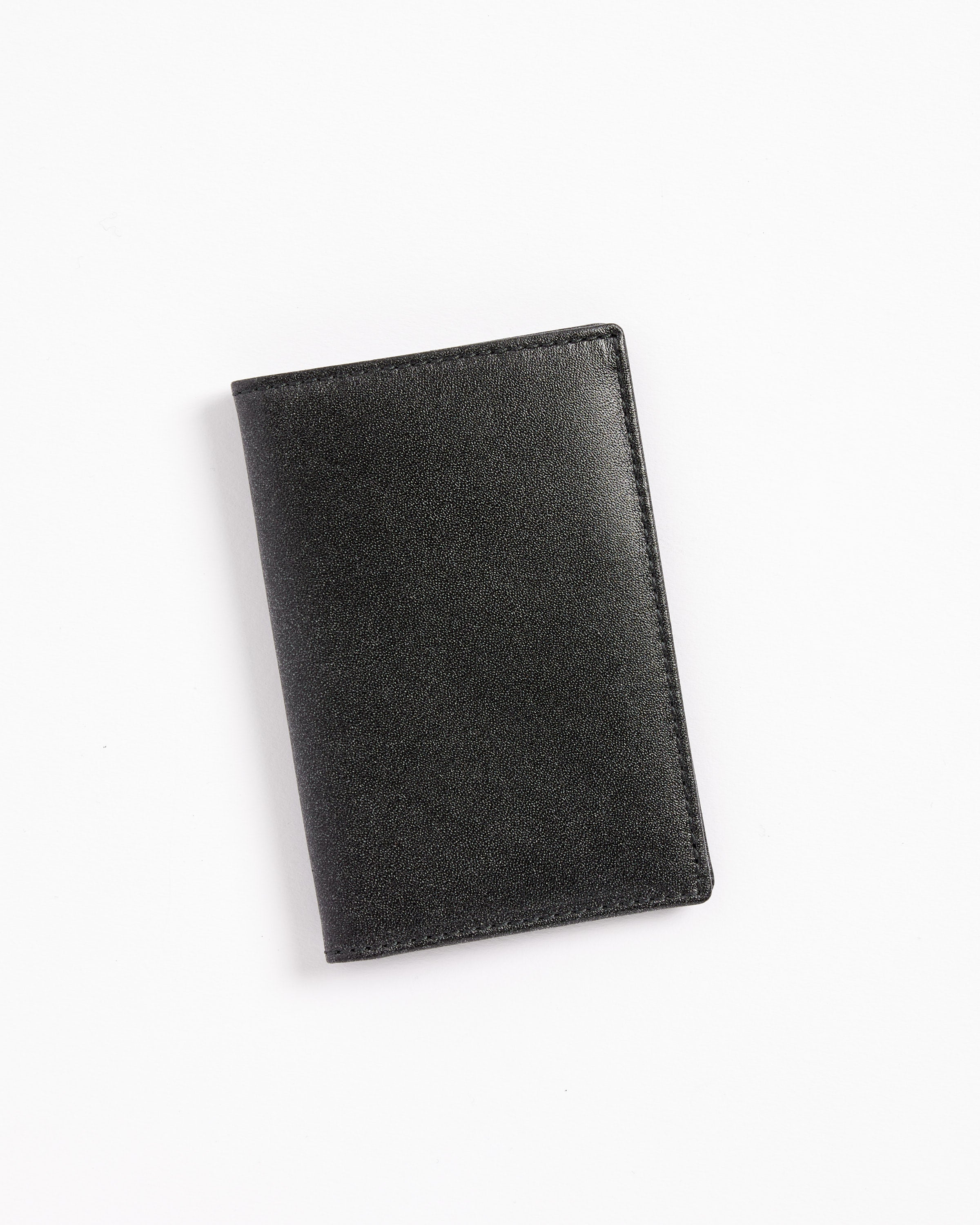 The Classic Cardholder in Black by Comme des Garcons Wallet, crafted from premium leather in Spain, is shown closed on a white background, viewed from above.