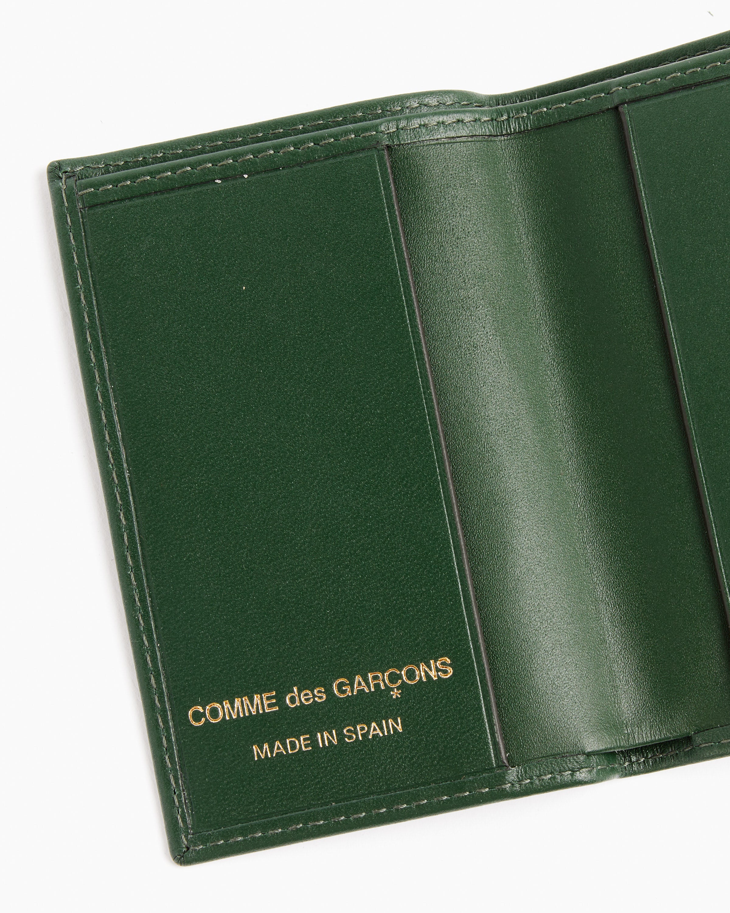The Classic Cardholder in Bottle Green by Comme des Garcons Wallet features green cowhide leather and gold COMME des GARÇONS and MADE IN SPAIN stamps inside.
