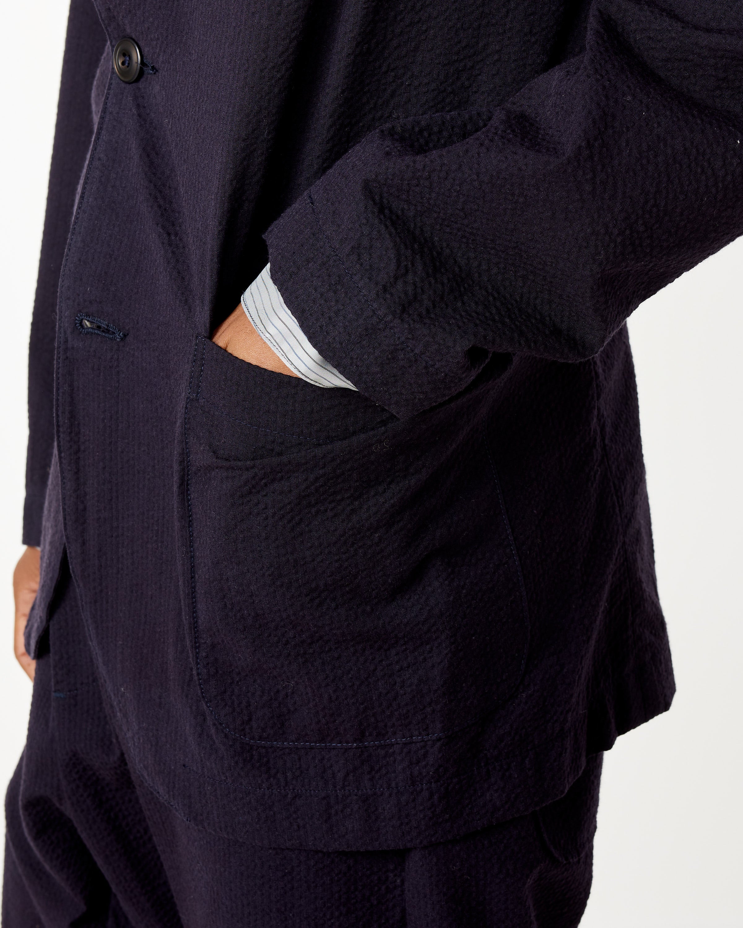 A person wearing the SMOCK Blazer in Seersucker Midnight with their hand in the front pocket, shown from the chest down against a plain white background.