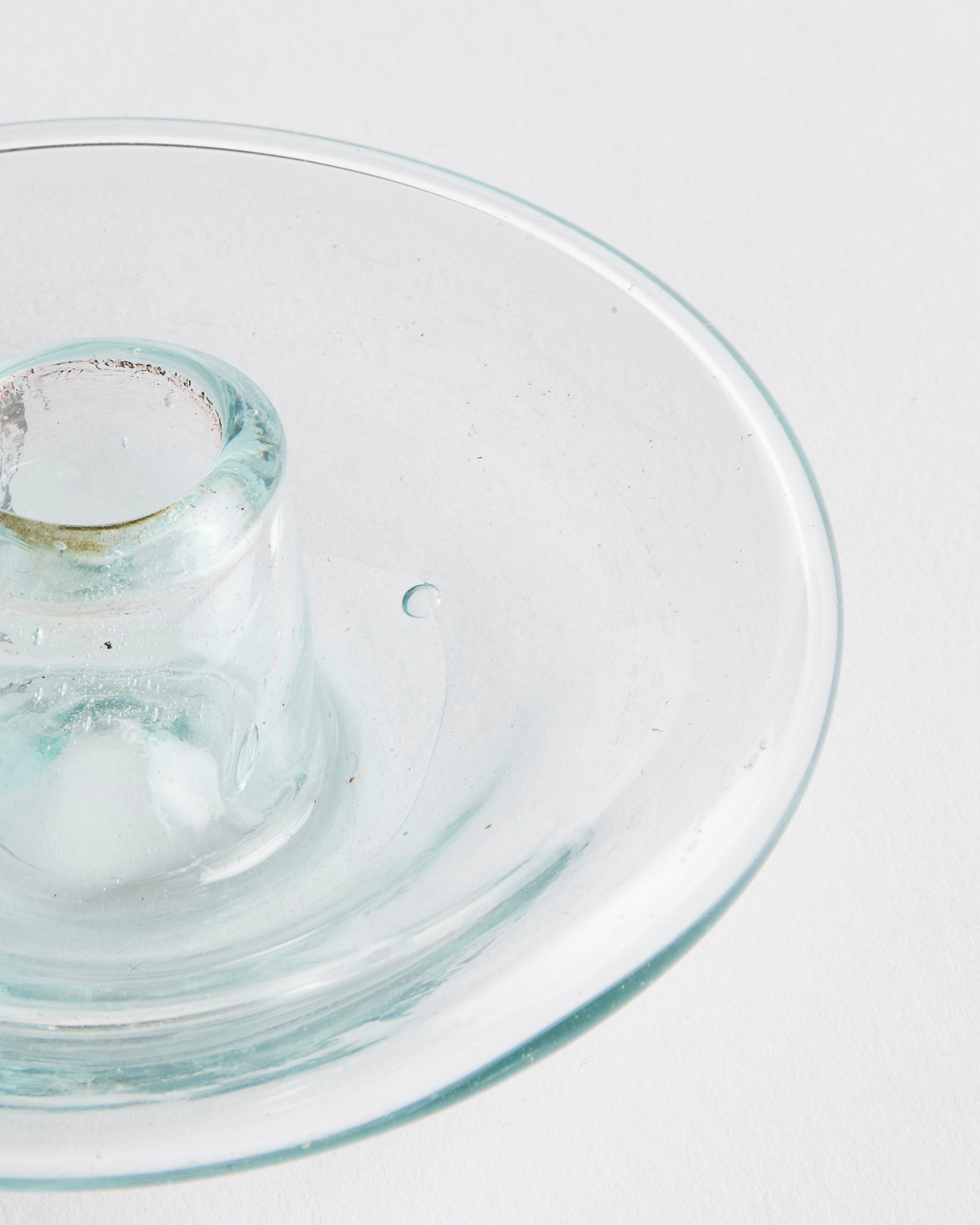 A close-up of the Incense Holder in Transparent by La Soufflerie, hand-blown from recycled glass with a central cylindrical slot, set against a white background.