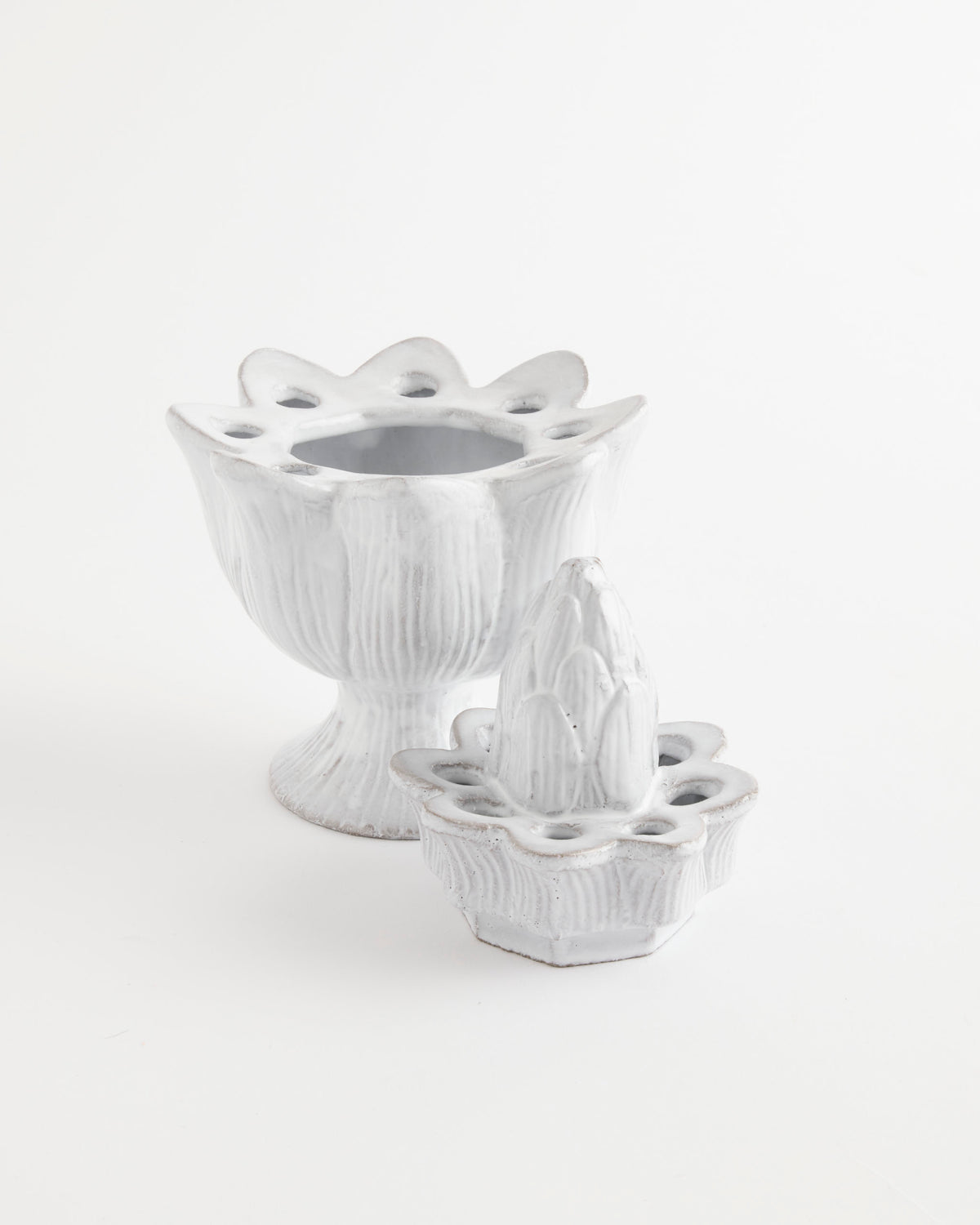 Two white ceramic Pique Flower Holders by Astier de Villatte—each with petal-shaped rims and vintage elegance—are displayed together, one standing upright and the other in front, both set against a plain white background.