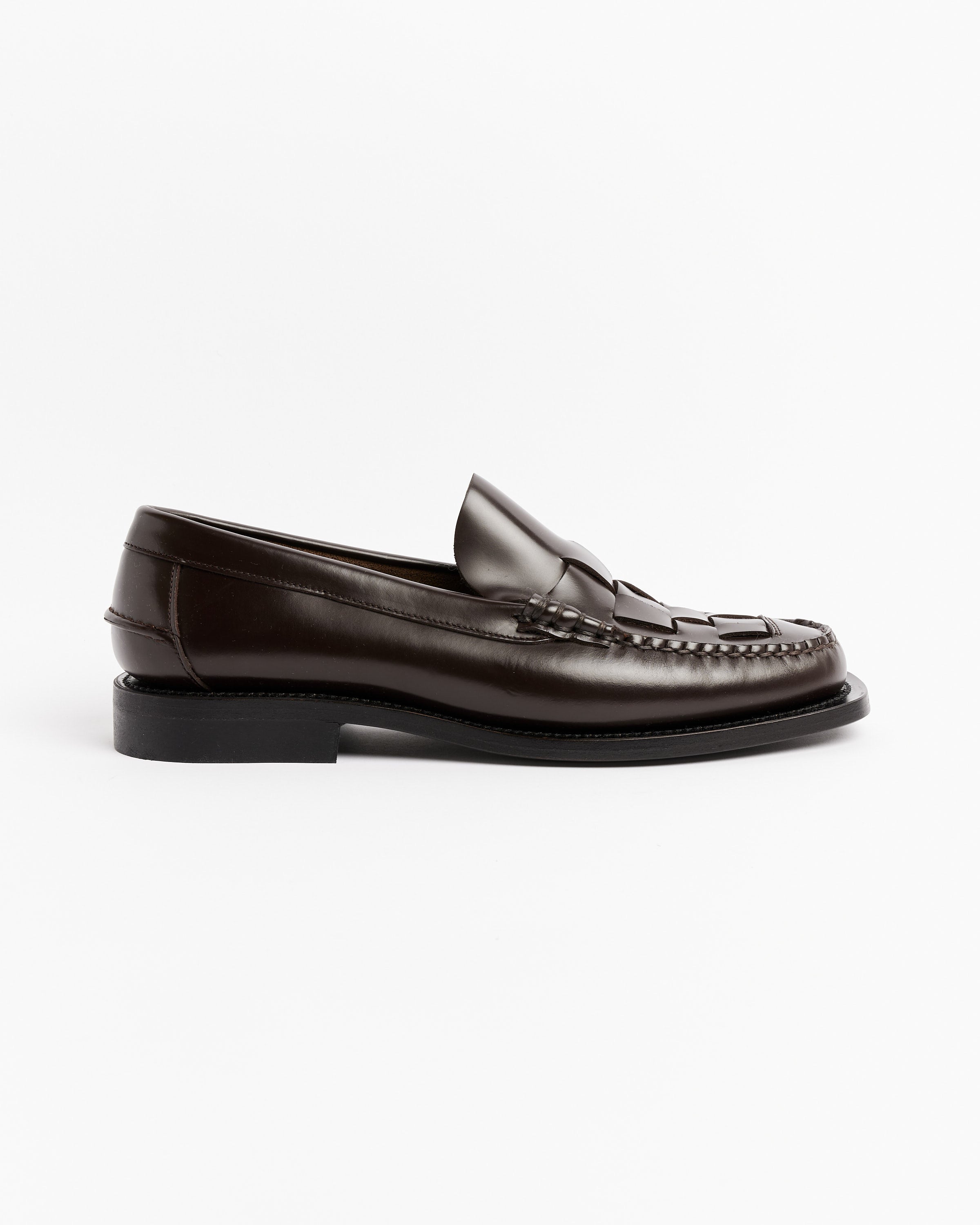 The Hereu Nombela Loafer in Dark Brown is a classic moccasin-style penny loafer crafted in Spain, featuring visible stitching, low heel, and a timeless side-profile design against a white background.