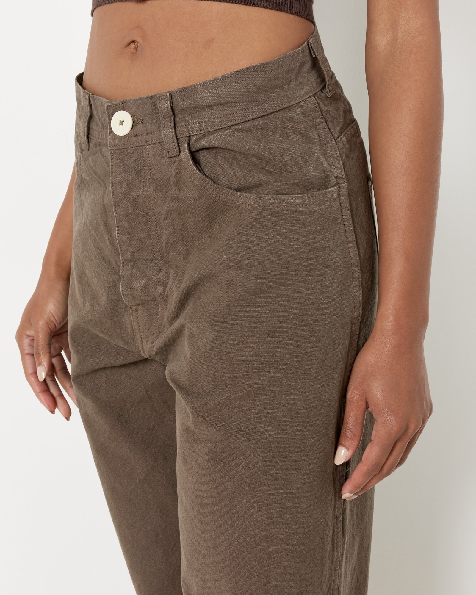 A person is shown from the waist down wearing Jesse Kamm’s California Wide Pant in Mushroom; one hand rests by their side while the other is partly in a pocket, styled with a cropped brown top.