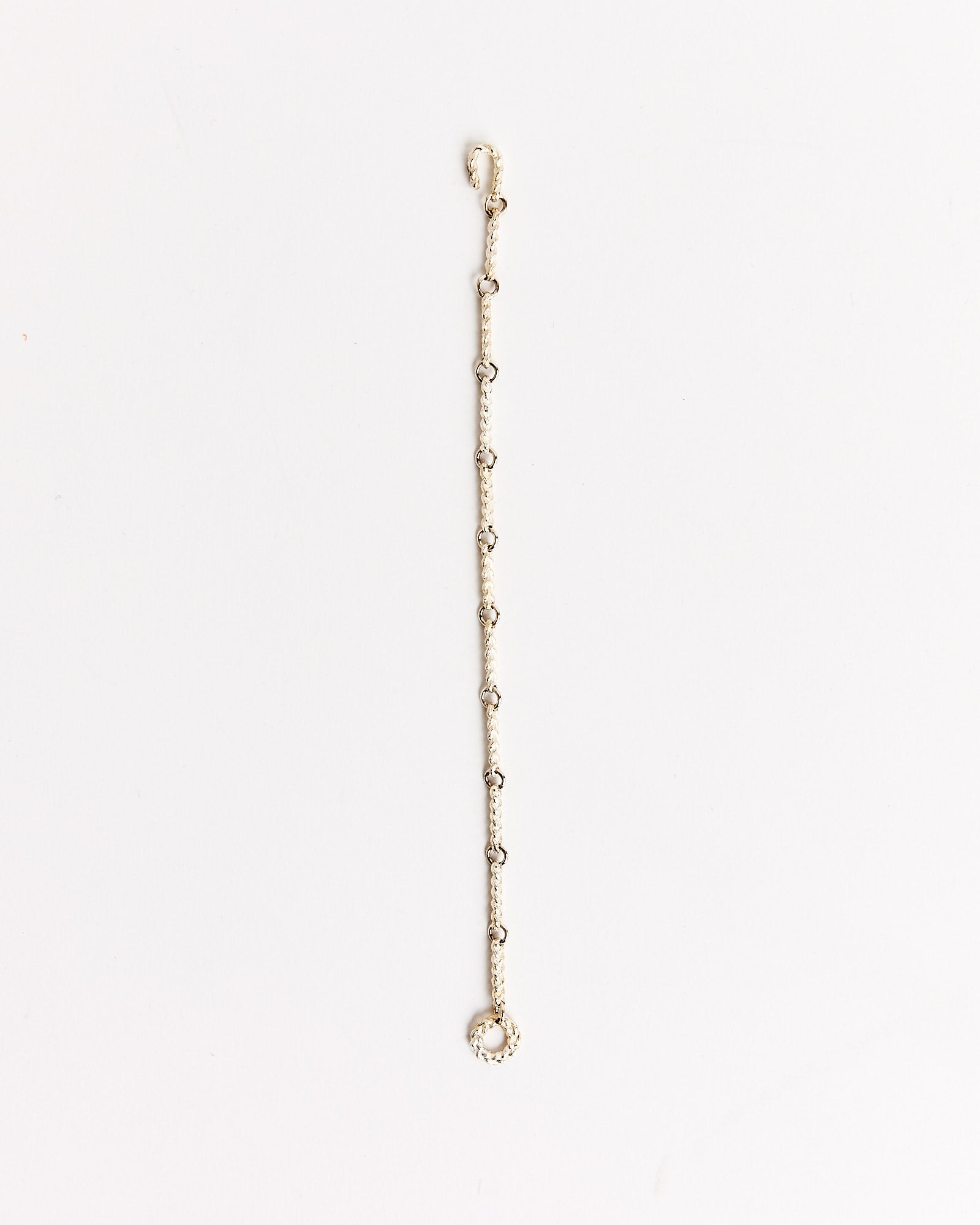 The Braided Link Bracelet in Silver by Bleue Burnham features fine, intertwined links and rests elegantly on a plain white background.