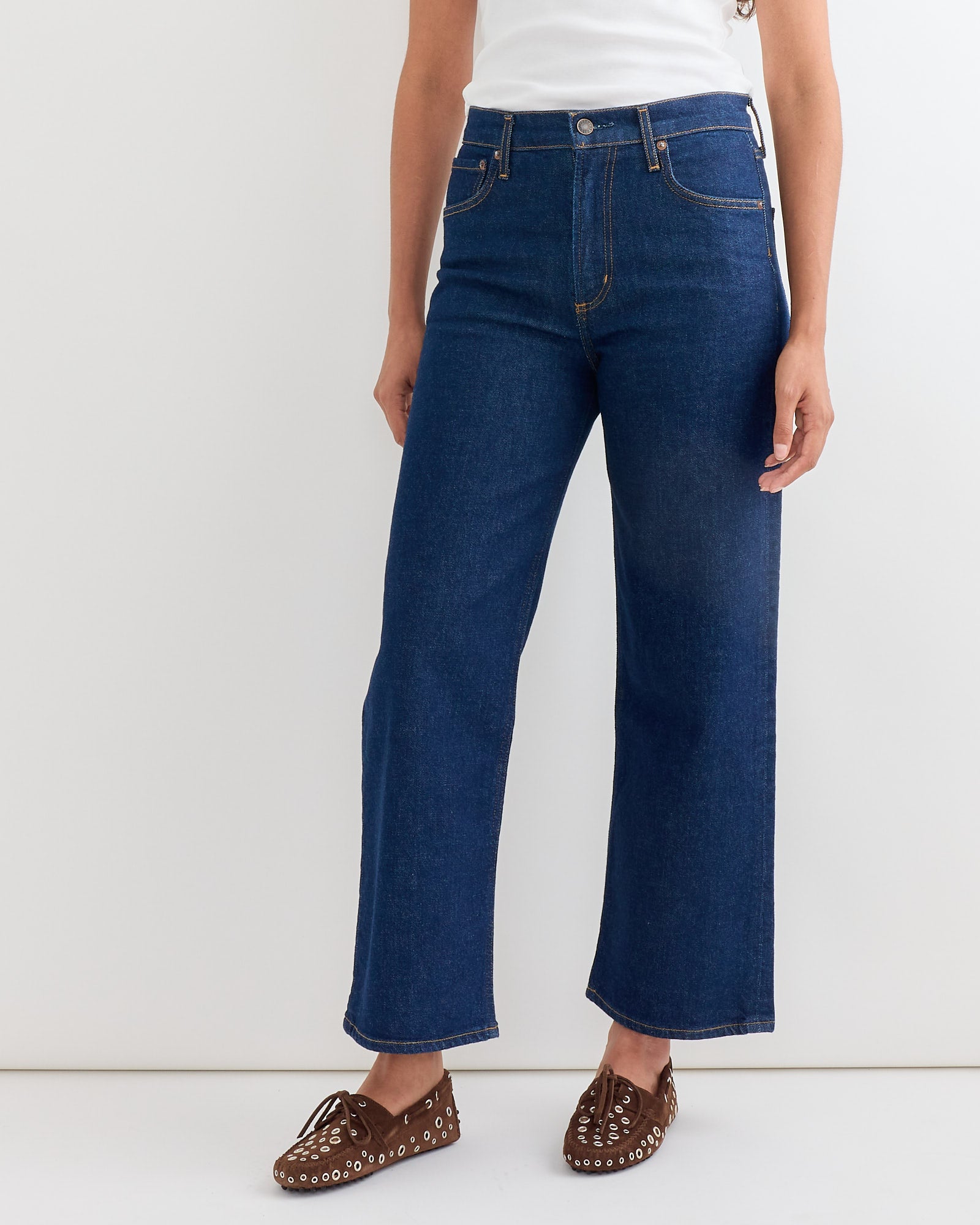 A person wears the AGOLDE Ren Jean in Reissue—high-waisted sustainable wide-leg denim—paired with a white top and brown woven loafers, standing against a plain white background.