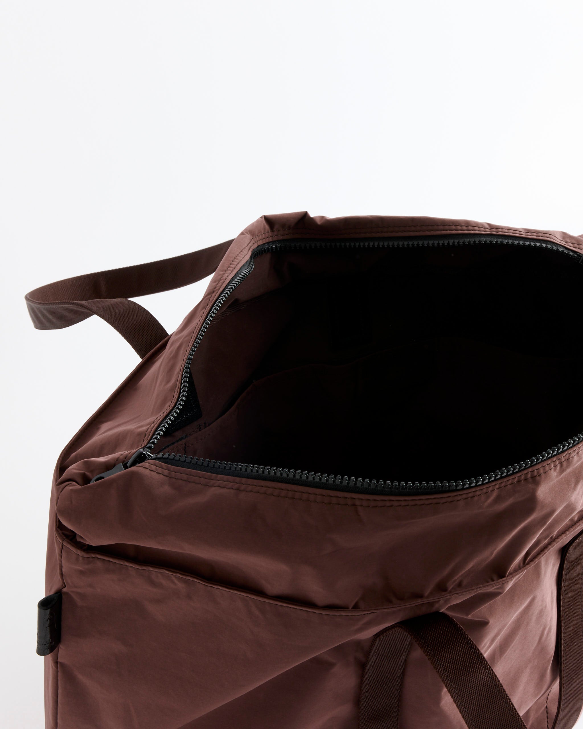 A close-up of the Amiacalva Gabardine Tote in Bordeaux Brown, featuring an open zippered design with a partially visible handle, reveals the interior against a plain white background.