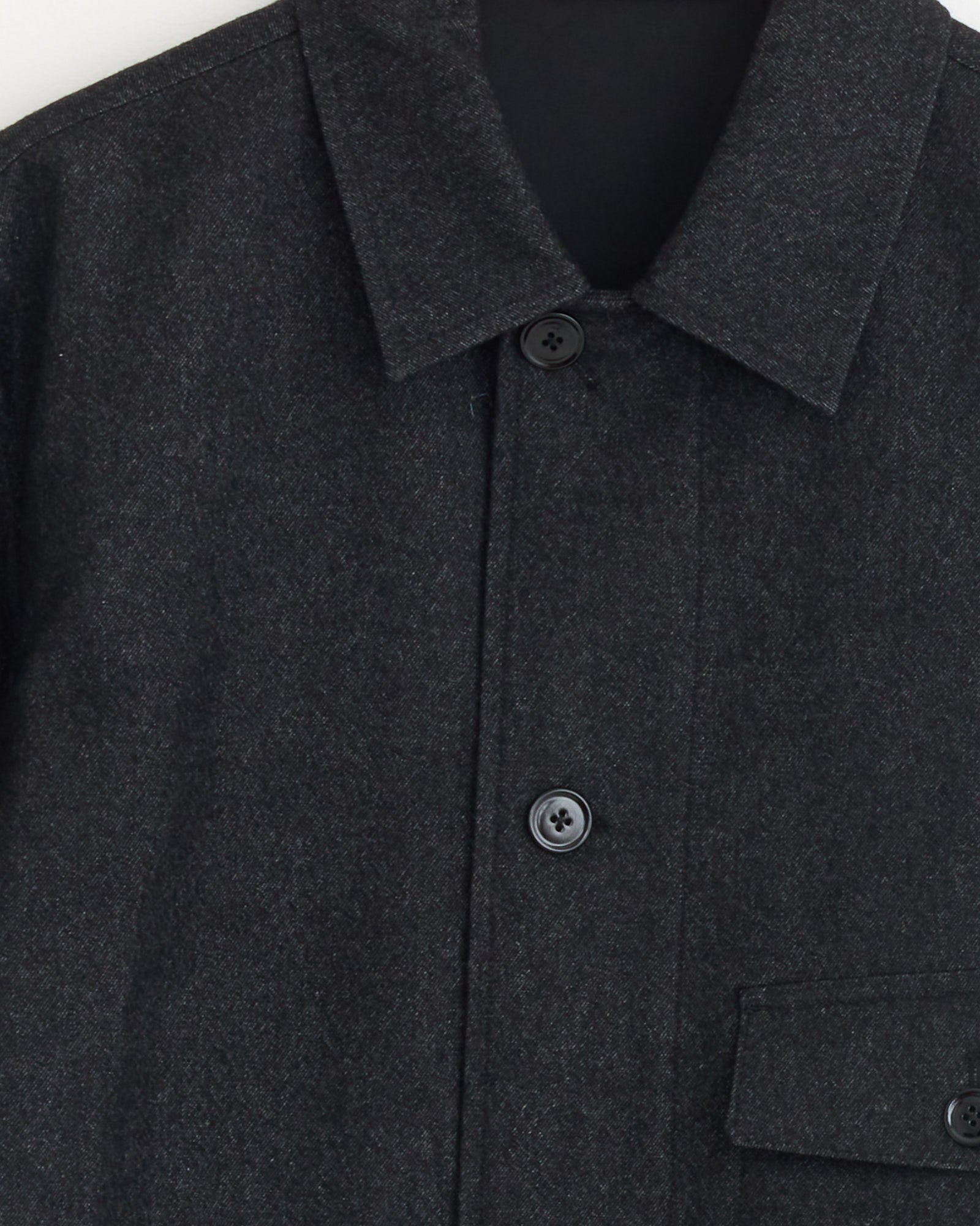 Close-up of the upper section of the Lemaire One Pocket Overshirt in Black/Grey Melange, showing a pointed collar, two visible black buttons, and a partly visible flap pocket at the bottom right.