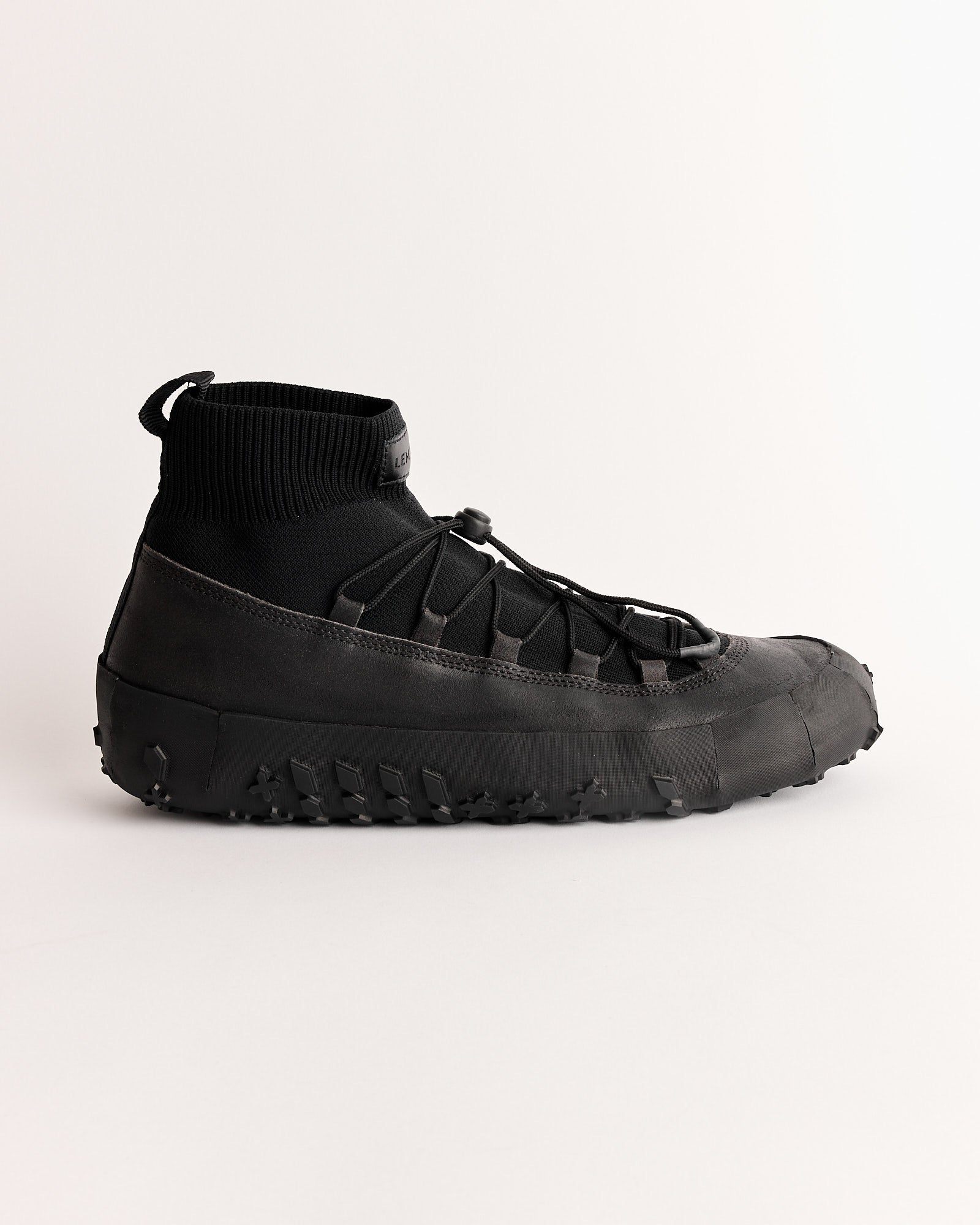 The Lemaire Vibram Wrap On Sneaker in Asphalt features a rugged waterproof Vibram sole, sock-like knit upper, pull tab at the heel, and unique lacing, shown on a plain light background.