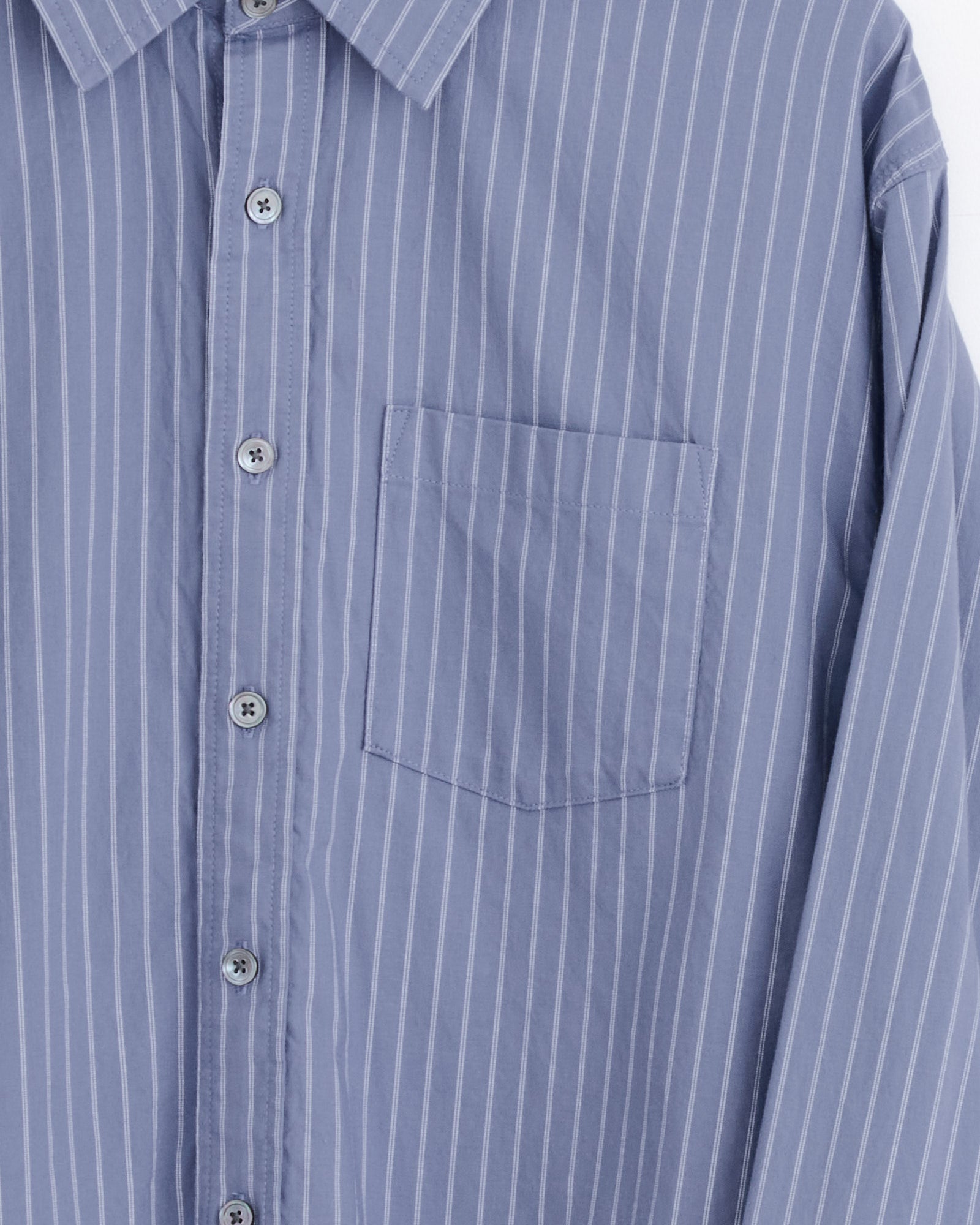 Close-up of the Stussy Oxford Shirt in Blue Stripe, featuring a boxy fit, white vertical pinstripes, a collar, and a left chest pocket.