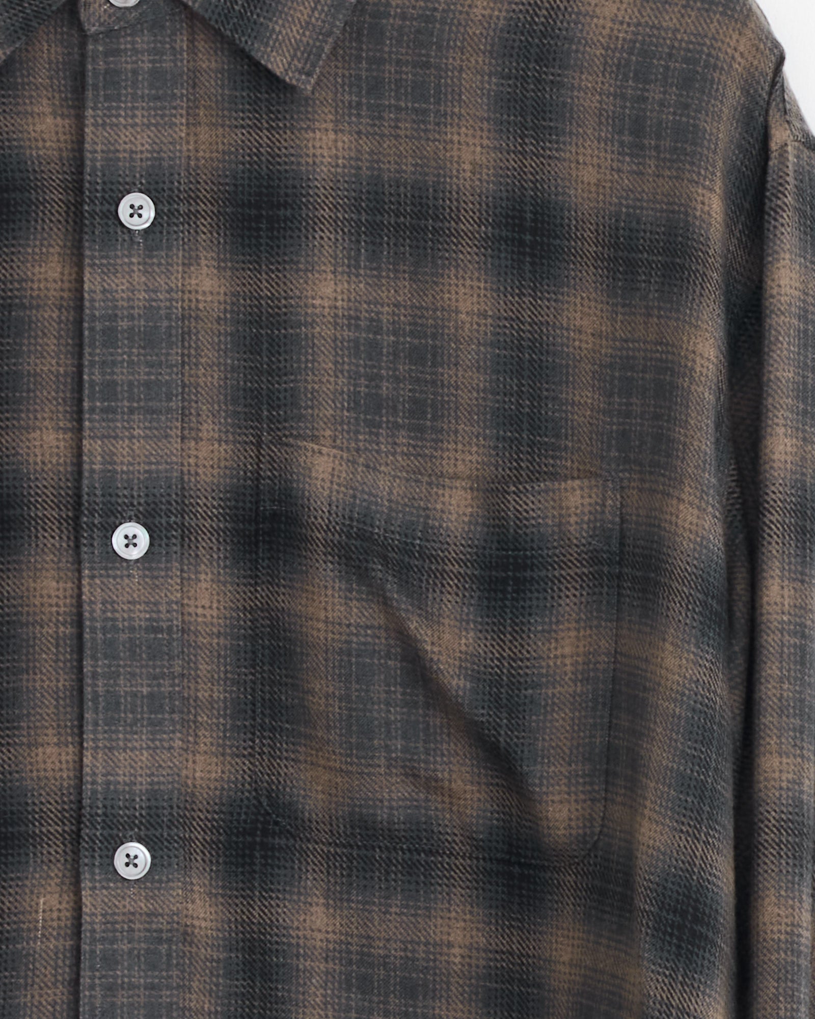 Close-up of the Stussy Matthew Plaid Shirt in Brown, showcasing its brushed cotton flannel, brown and black pattern, white buttons, classic fit, part of the collar, and chest with a subtle pocket.