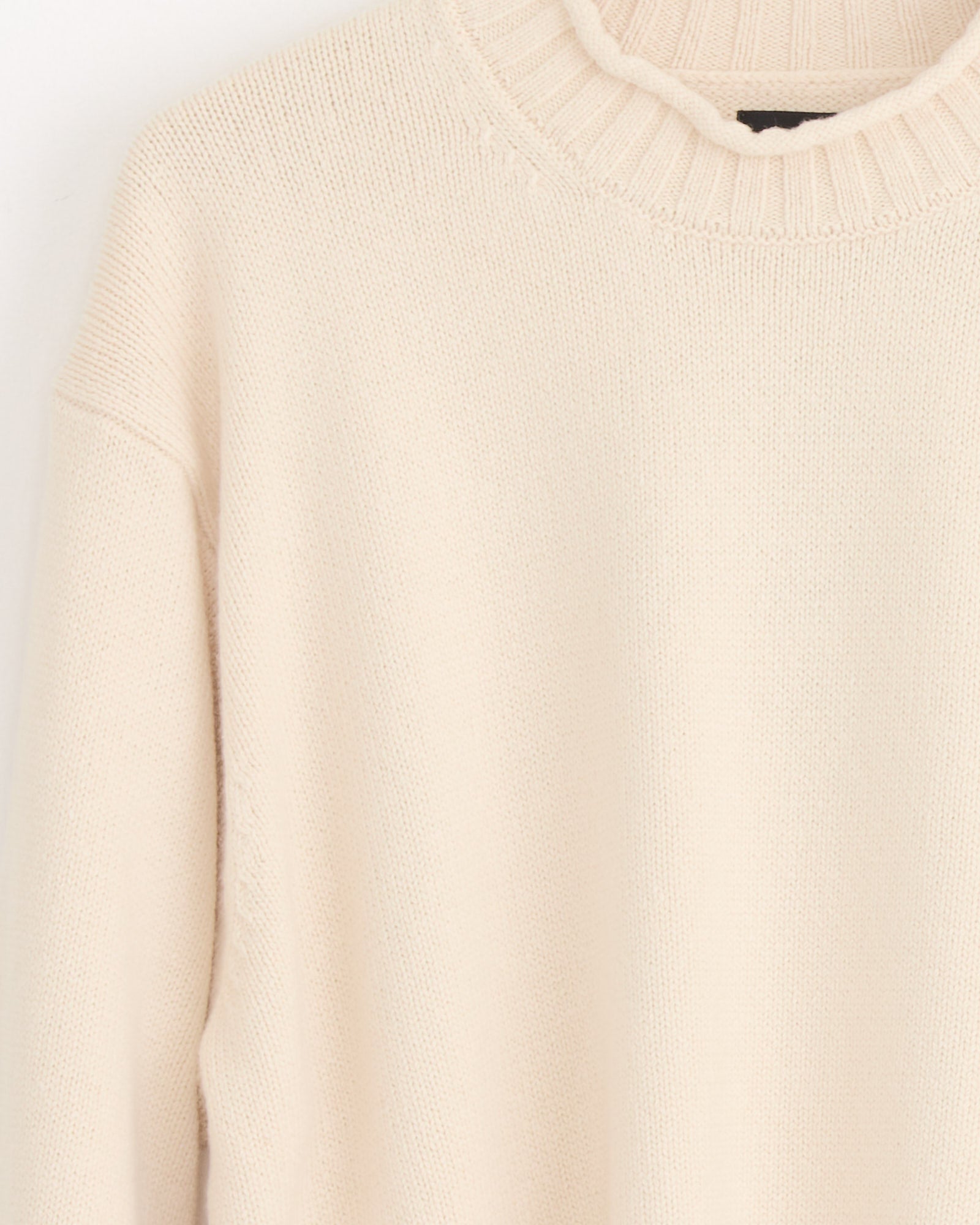 A close-up of the Stussy Tonal Mock Neck Sweater in Natural, featuring a cream hue and ribbed mock neckline, displayed against a plain light background.