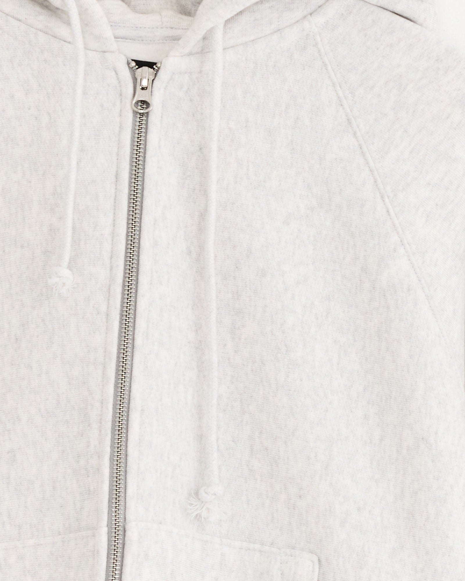 Close-up of the Stussy Raglan Zip Hoodie in Ash Heather, showing a soft, heavyweight cotton fleece with white drawstrings, a front zipper, and hood. Only part of this textured hoodie is visible.
