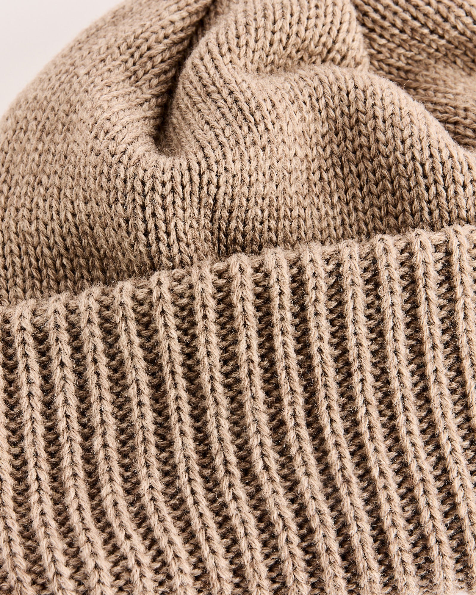 Close-up of the WINDSTOPPER® Beanie in Beige by Nanamica, featuring detailed ribbed and smooth knit textures in lightweight acrylic wool.