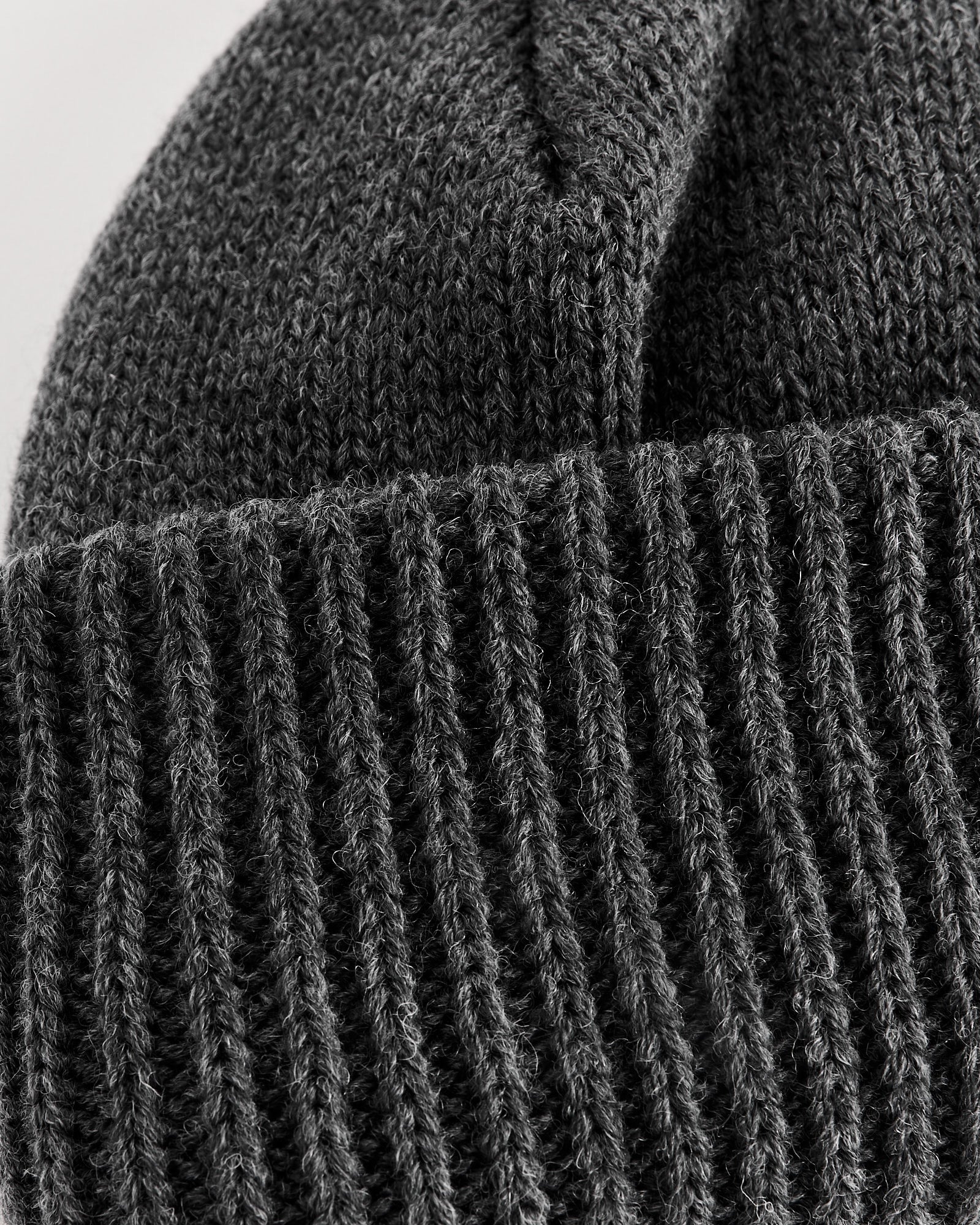 Close-up of the Nanamica WINDSTOPPER® Beanie in Heather Grey, featuring a ribbed fold-over brim and textured stitching.