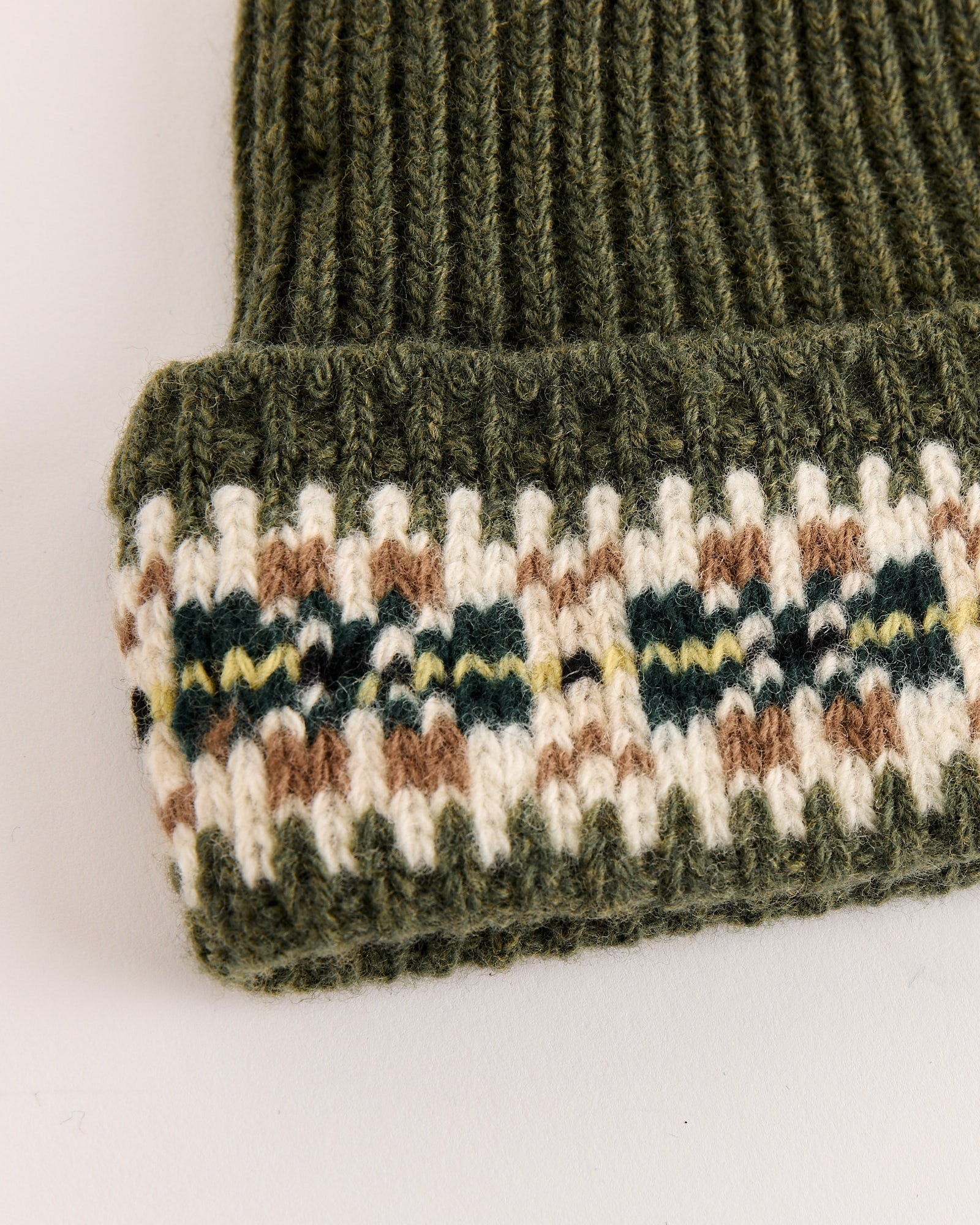 Close-up of the Moritz Hat in Green Multi by Bode, crafted in dark green merino wool with a ribbed texture and a folded brim featuring Fair Isle stripes in cream, brown, and dark green.