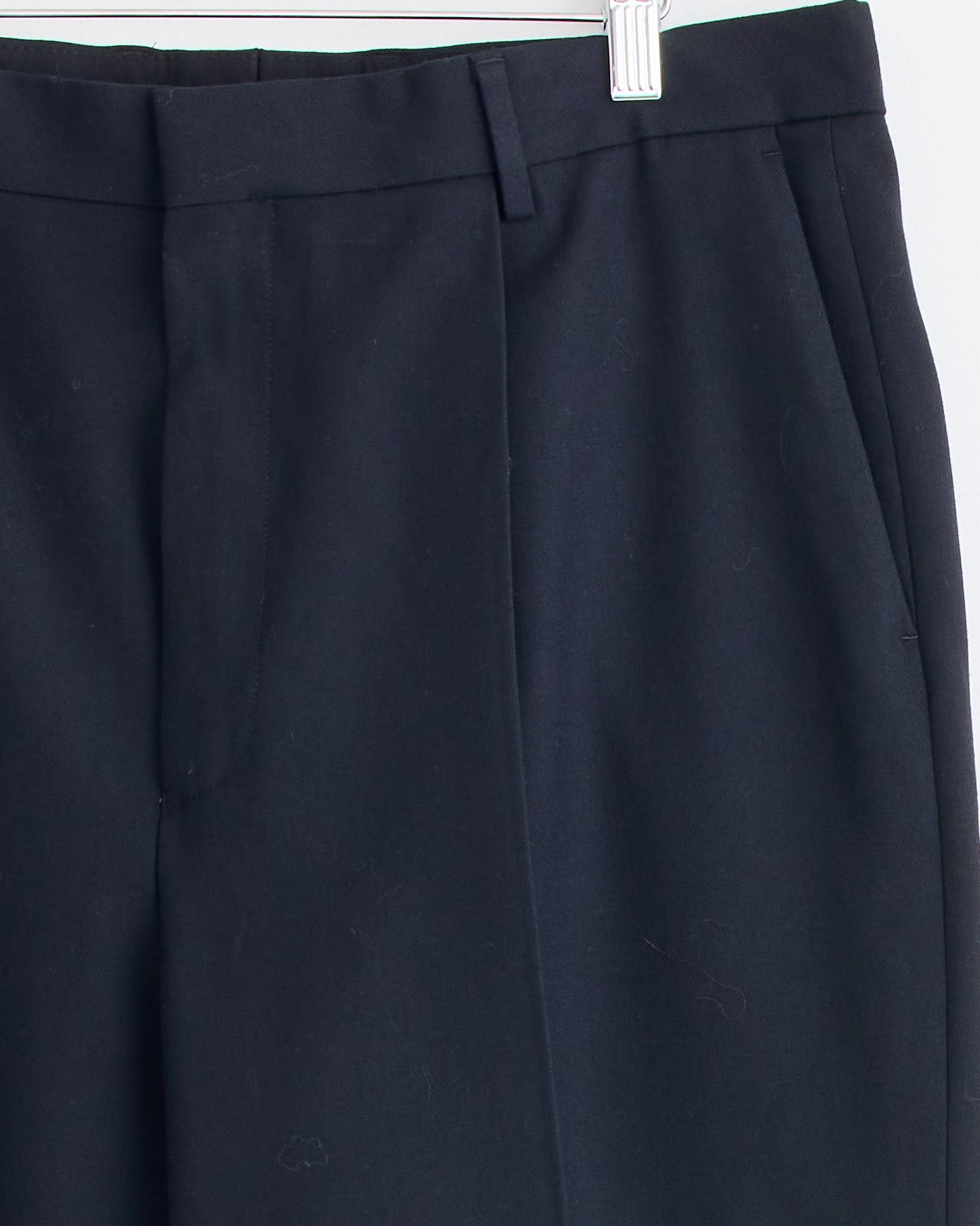 Close-up of Dries Van Noten’s Kiel 2246 Suit in Black pants on a hanger, focusing on the waistband, belt loops, zipper, and side pocket.