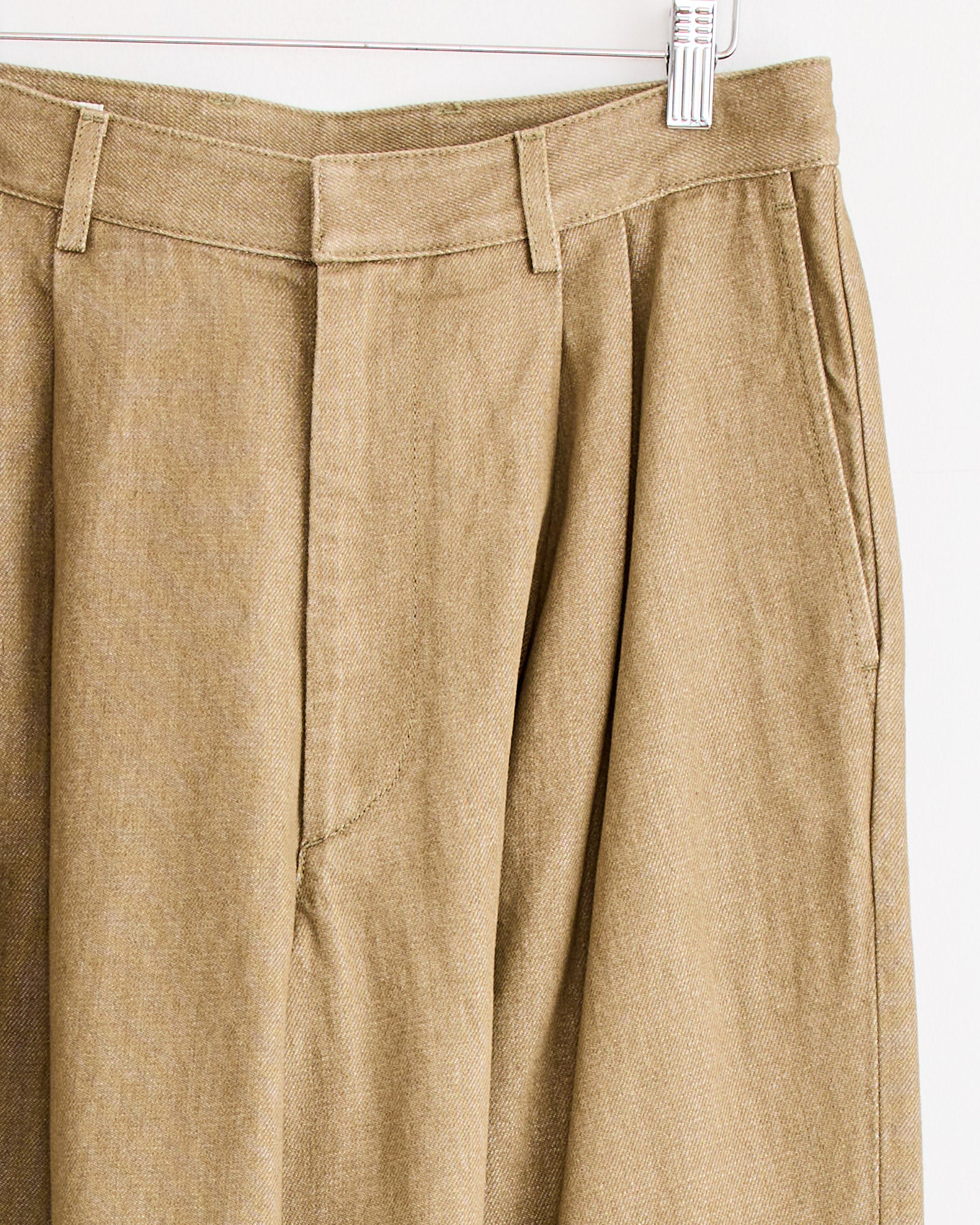 Pleated Denim Pant in Stone by Dries Van Noten on a white hanger, close-up highlighting the waistband, belt loops, and front pockets.