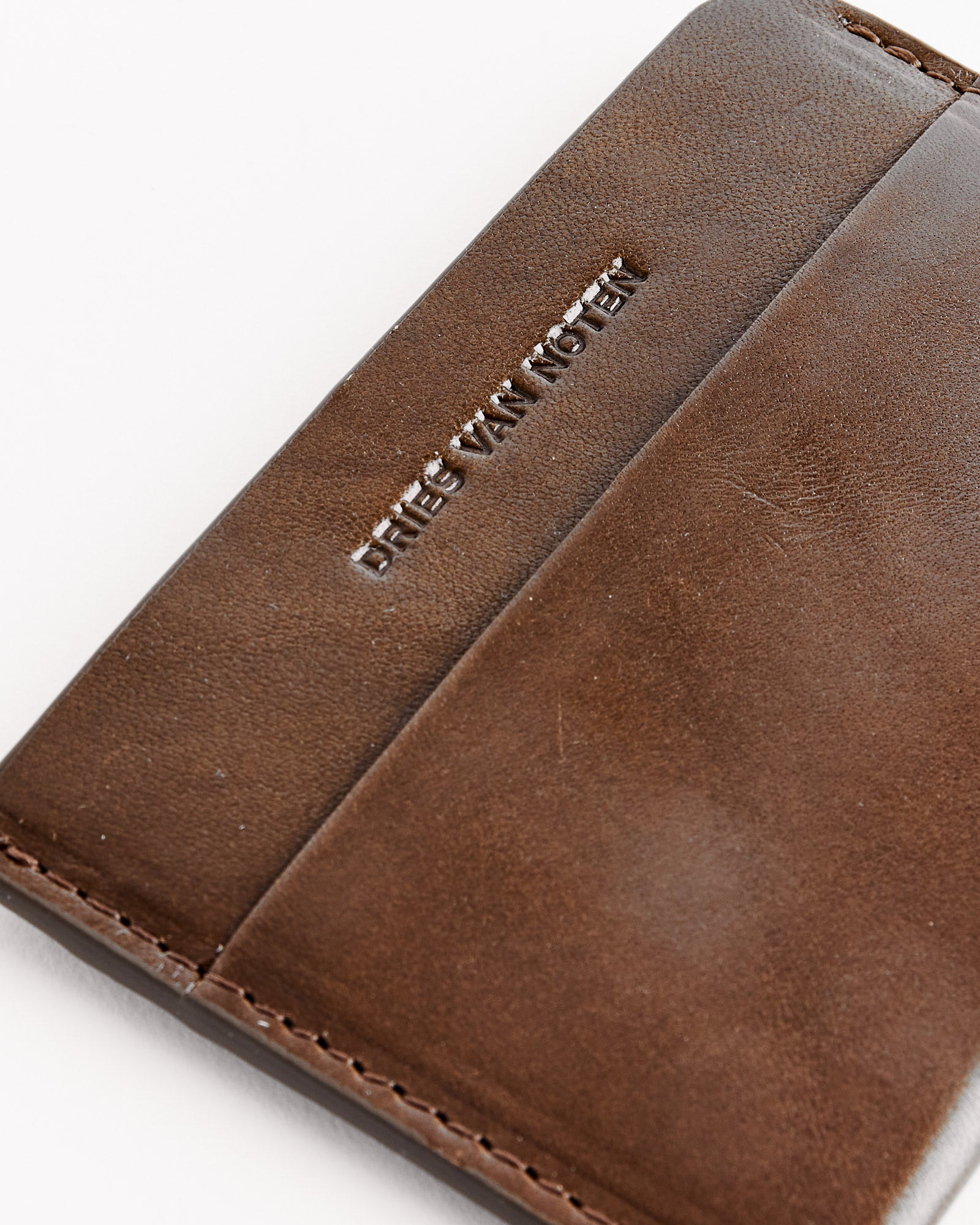 Close-up of a Dries Van Noten 241-151 Leather Card Case in olive with visible stitching and "DRIES VAN NOTEN" embossed. Made in Italy, the cardholder is shown on a white background.