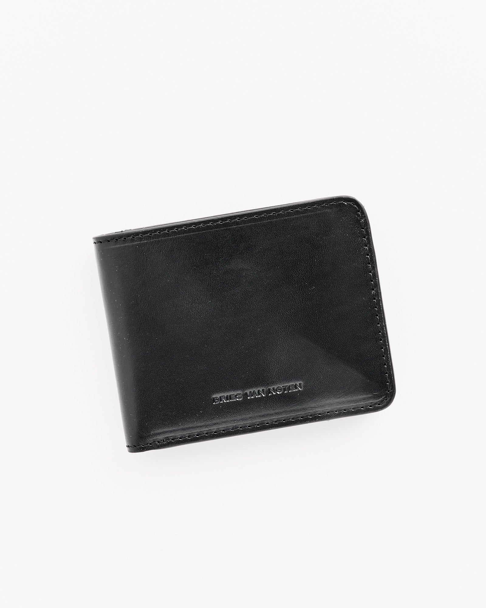 The Dries Van Noten 995-151 Wallet in Black, featuring subtle edge stitching and discreet embossed text near the bottom, is displayed closed against a white background.