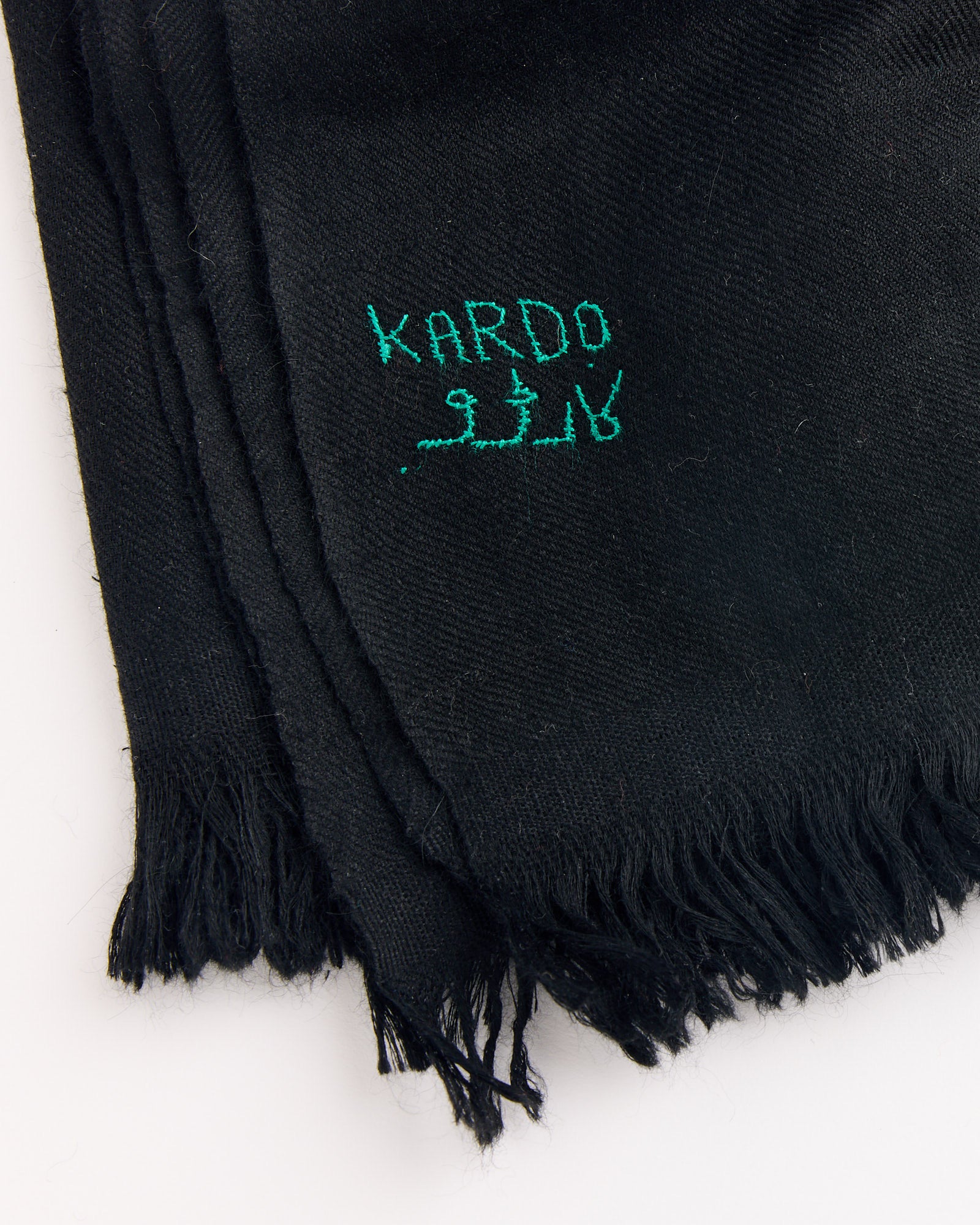 The Handwoven Pashmina Bandana in Black by Kardo features green "KARDO" embroidery in English and Arabic on black fabric, showcased on a white background.