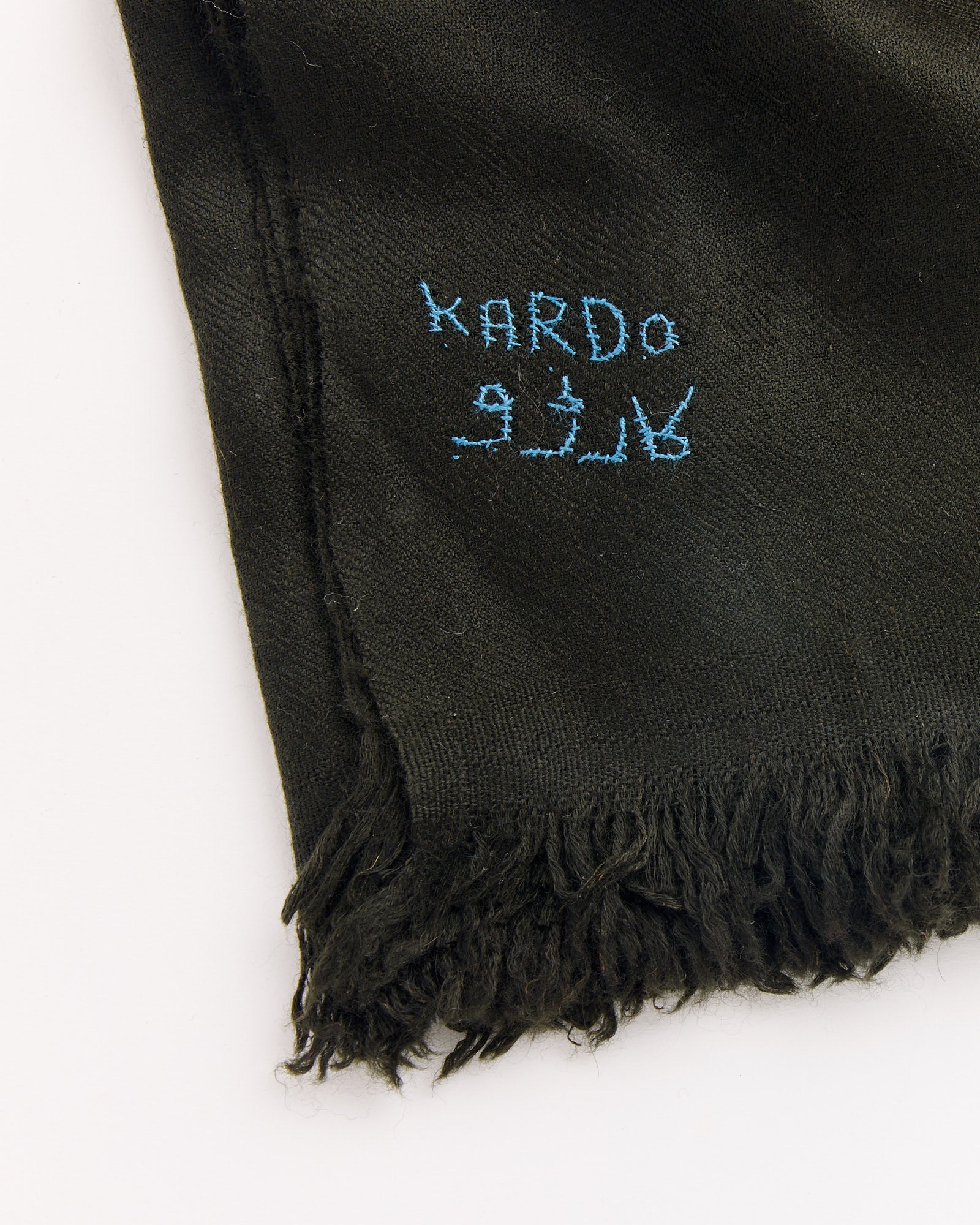 A dark green handwoven Pashmina bandana by Kardo features KARDO and other characters stitched in blue on one corner, displayed against a white background.