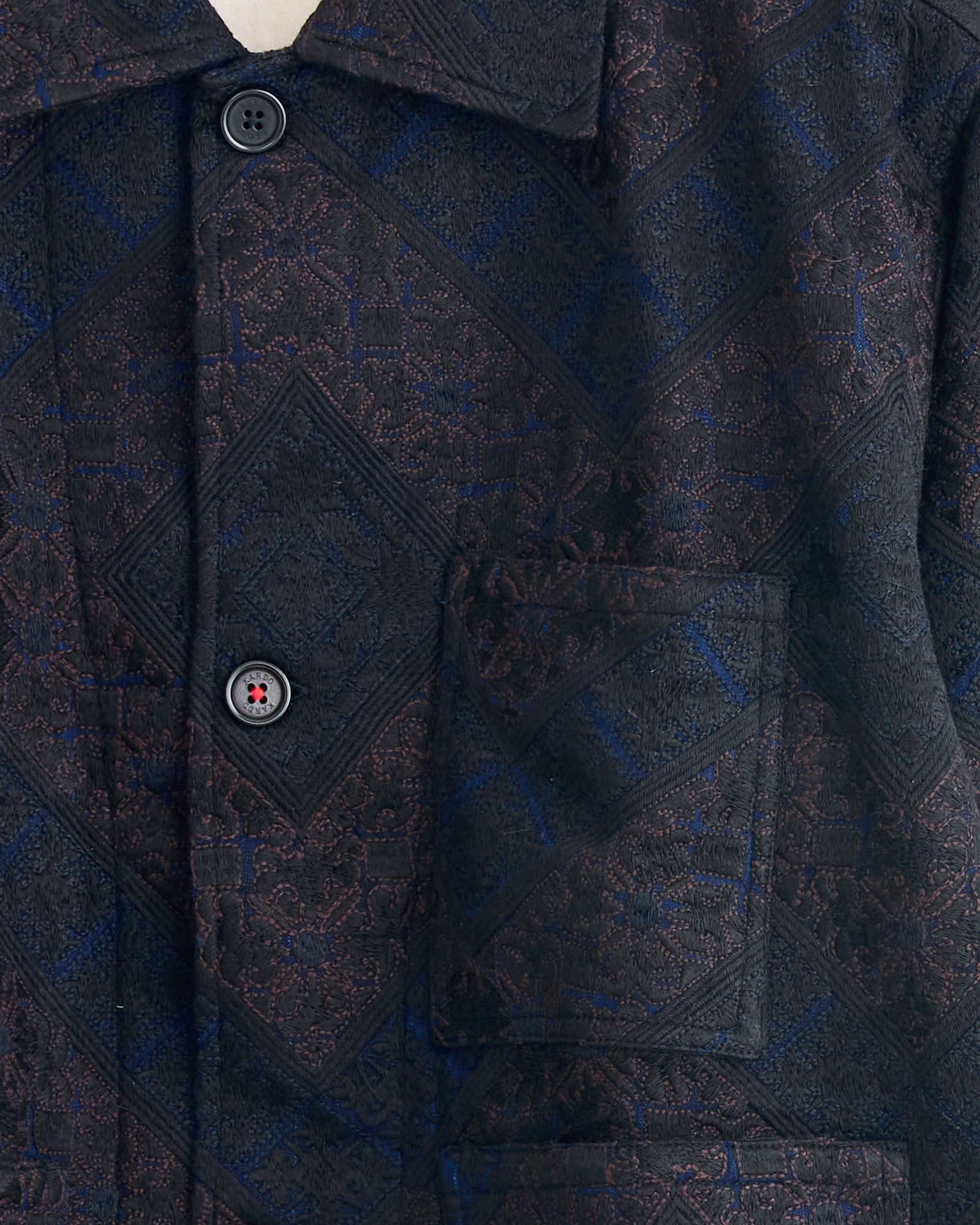 Close-up of the Kardo Bodhi Jacket in Indigo, featuring an intricate diamond pattern in black, blue, and purple, two black buttons, and a front patch pocket. For sizing or fit, please use our online chat.
