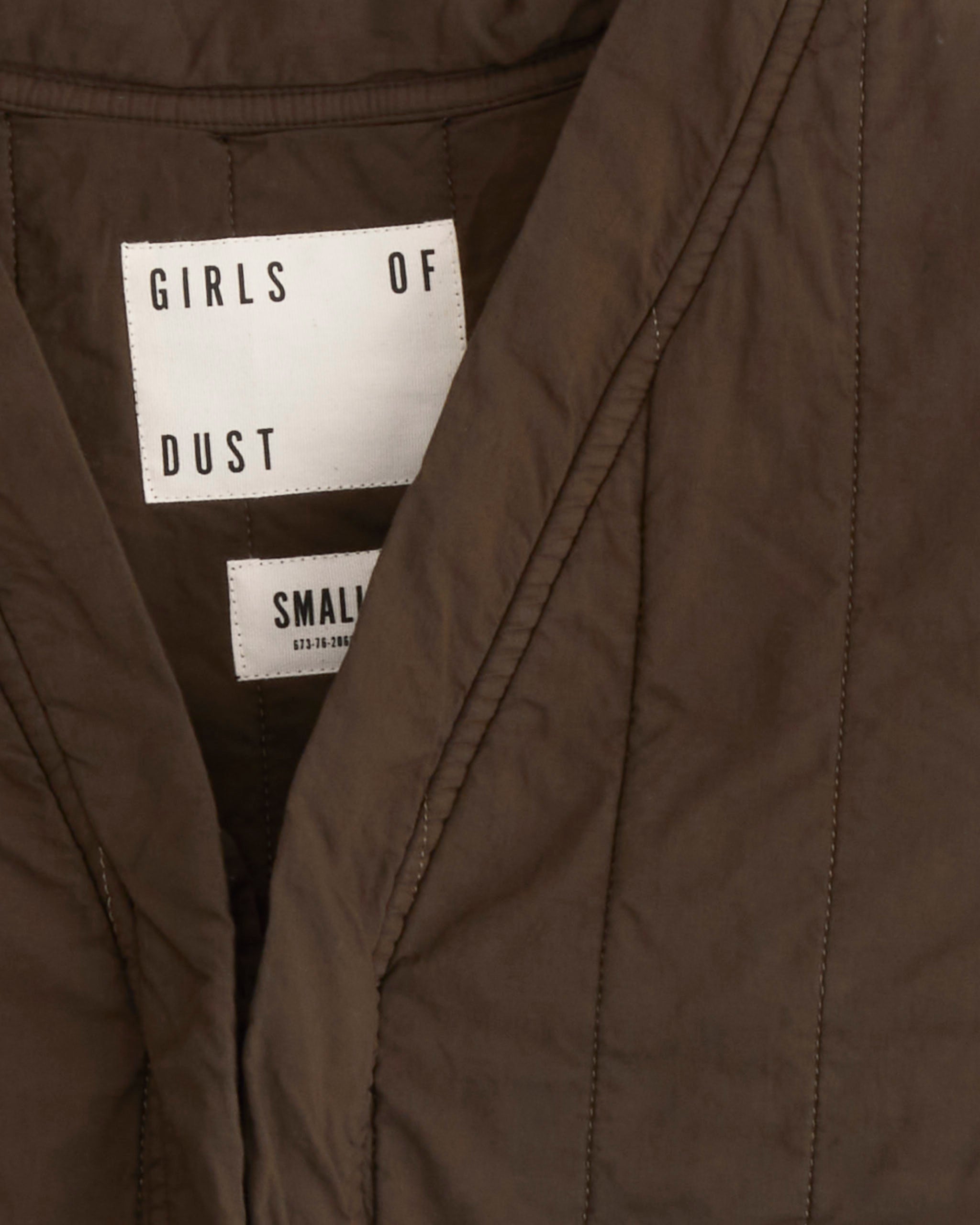 Close-up of the Girls of Dust Cork Vest in Java Brown, featuring a quilted cotton design and a white inner collar label showing the brand name and size Small.