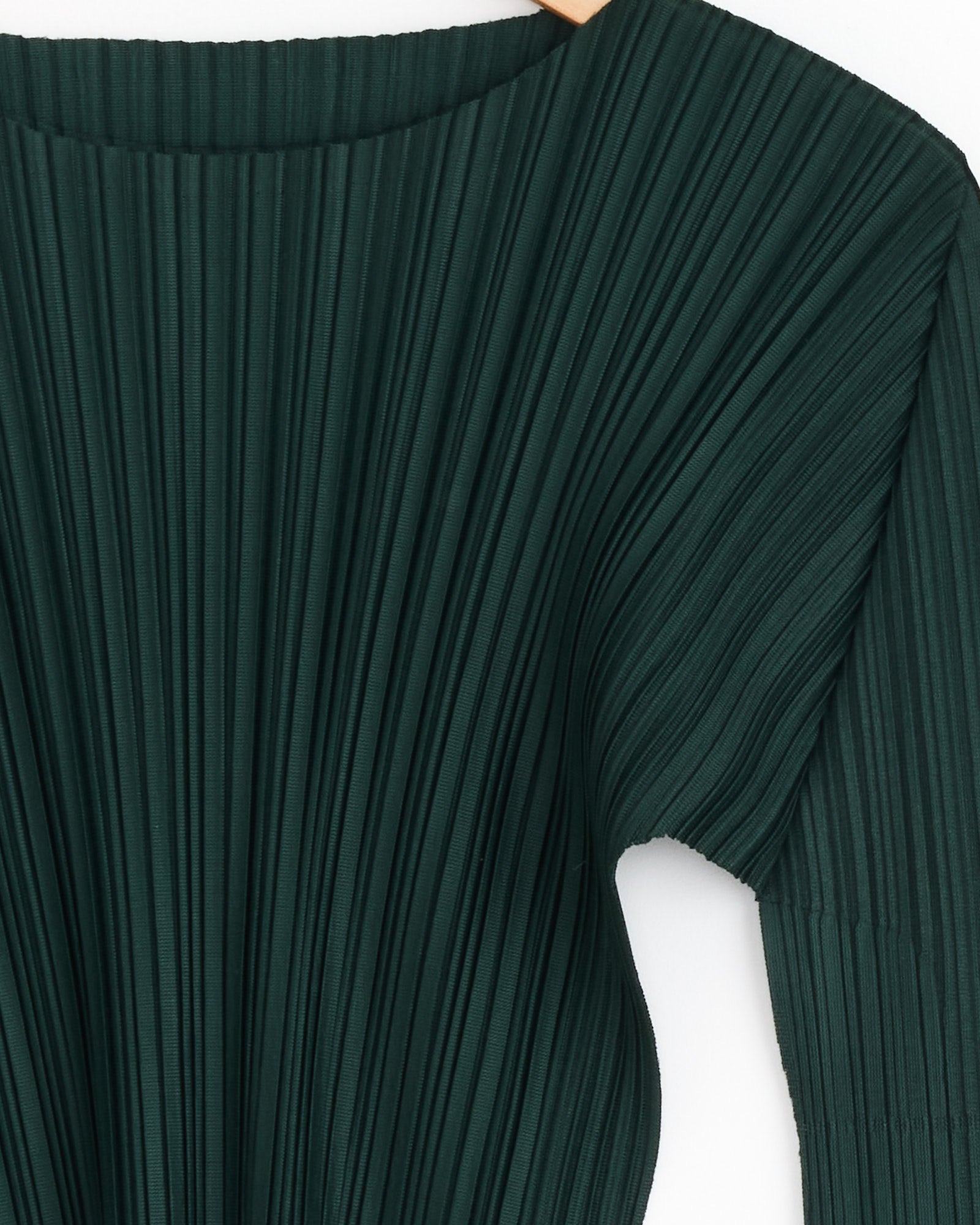 Close-up of the Soft Top in Dark Green by PLEATS PLEASE ISSEY MIYAKE, showcasing a wide boat neckline, long sleeves, and evenly spaced vertical pleats that add texture against a white background.
