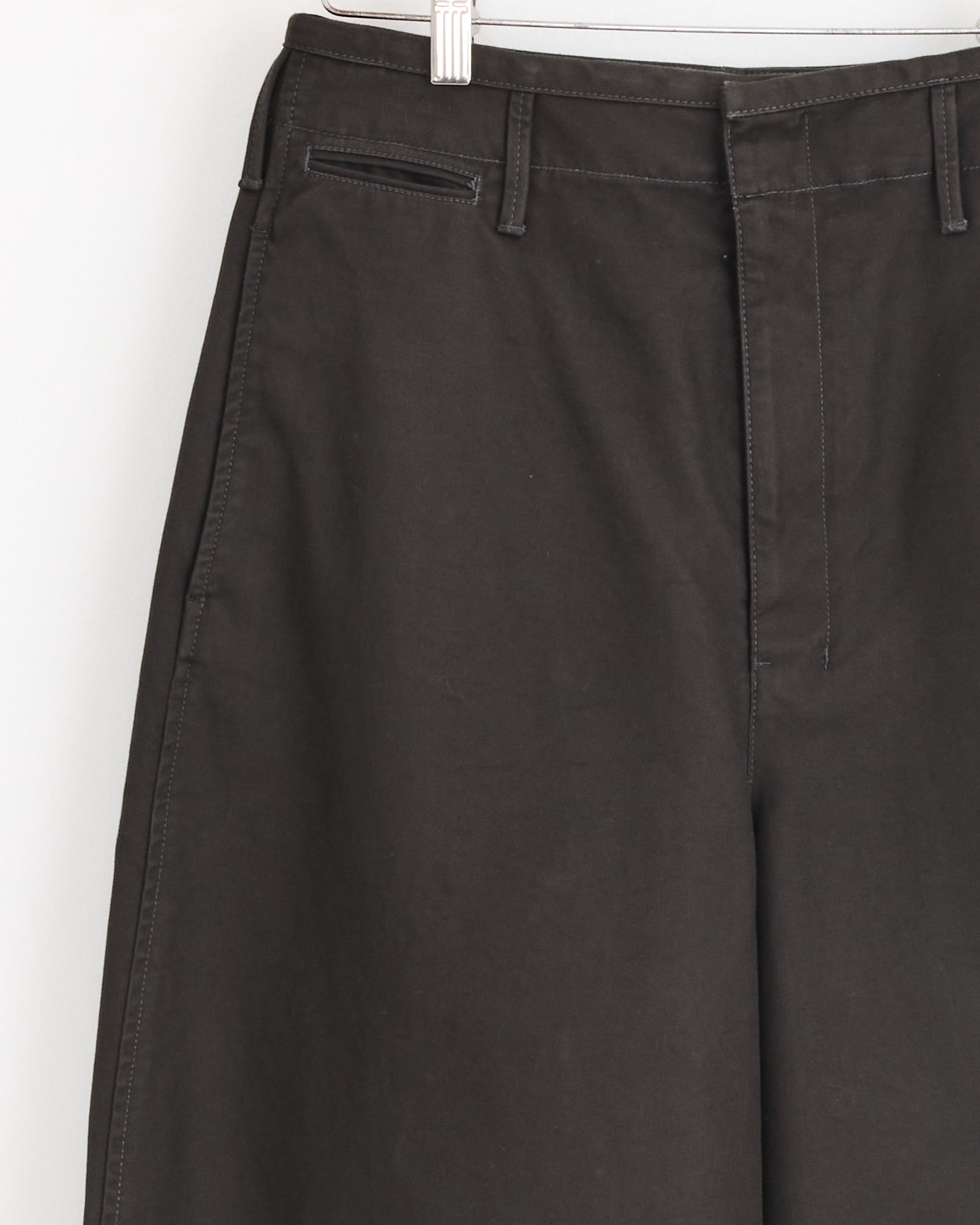 Close-up of the Lemaire Large Chino in Espresso, made from dark Japanese cotton twill. Features include an oversized cut, belt loops, hidden front zipper, and a right-side single welt pocket.