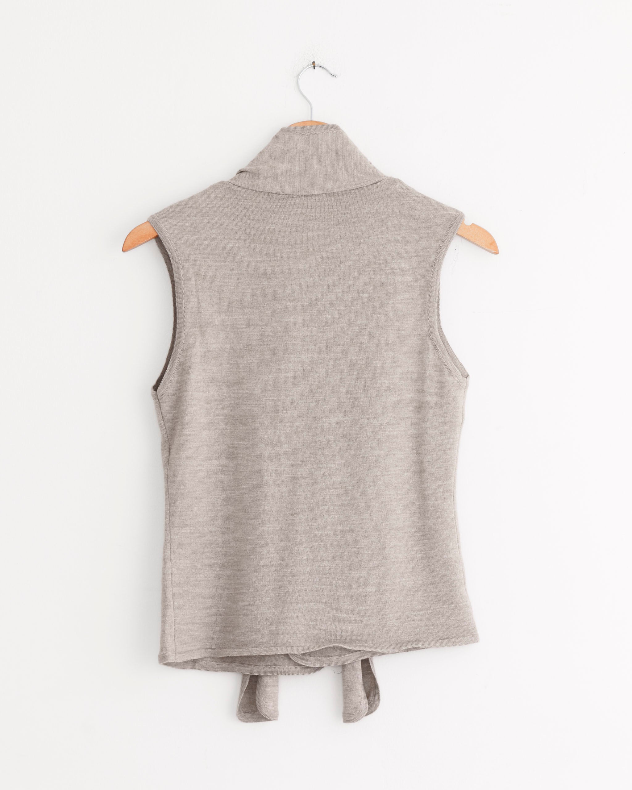 The Lemaire Asymmetrical Sleeveless Cardigan in light taupe hangs on a wooden hanger against a white background, showcasing its refined style from the back.