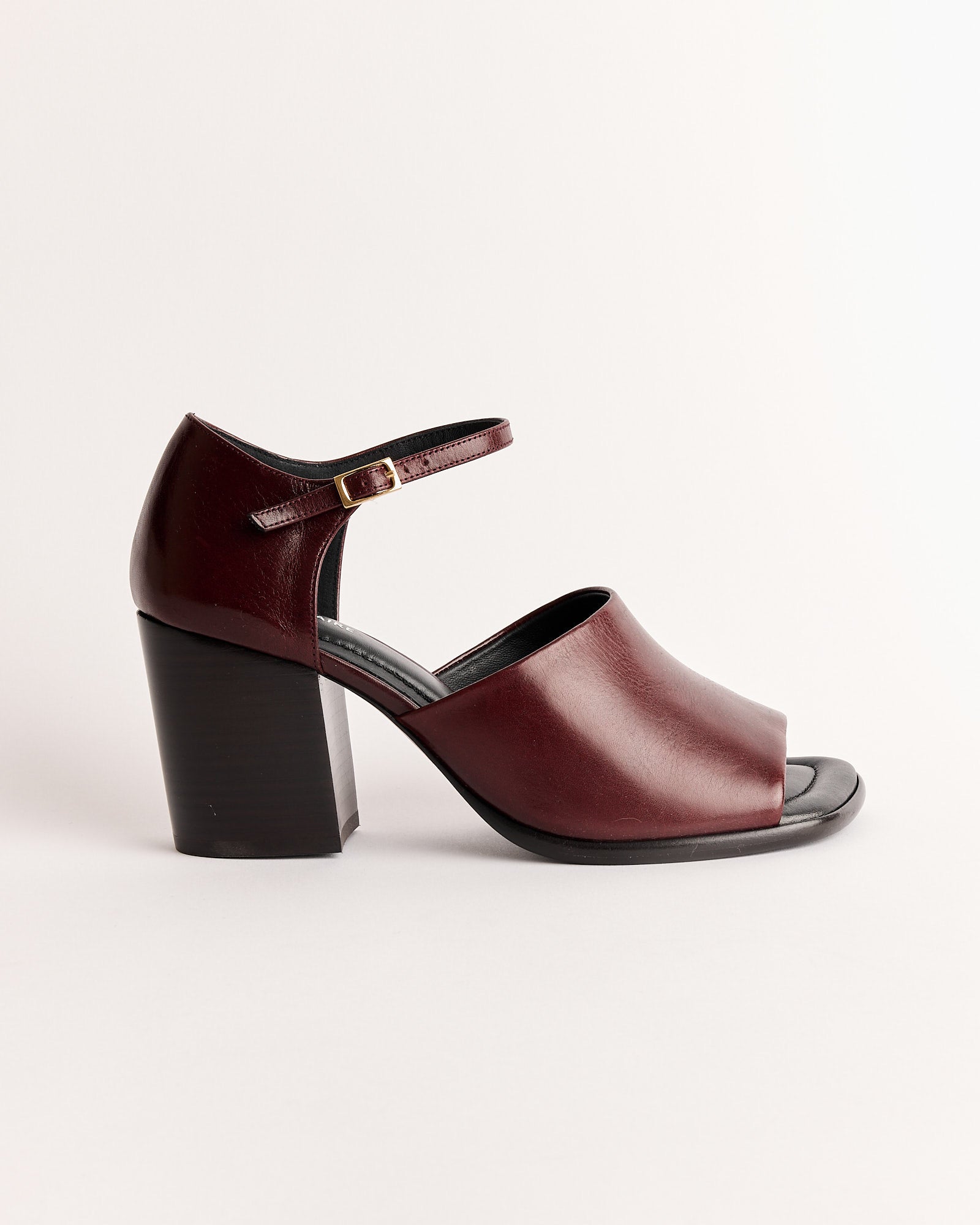 The Lemaire Square Heeled Sandal in Chianti features premium Italian vegetable-tanned burgundy leather, an open toe, closed heel, ankle strap with gold buckle, and square heel, shown against a plain light background.