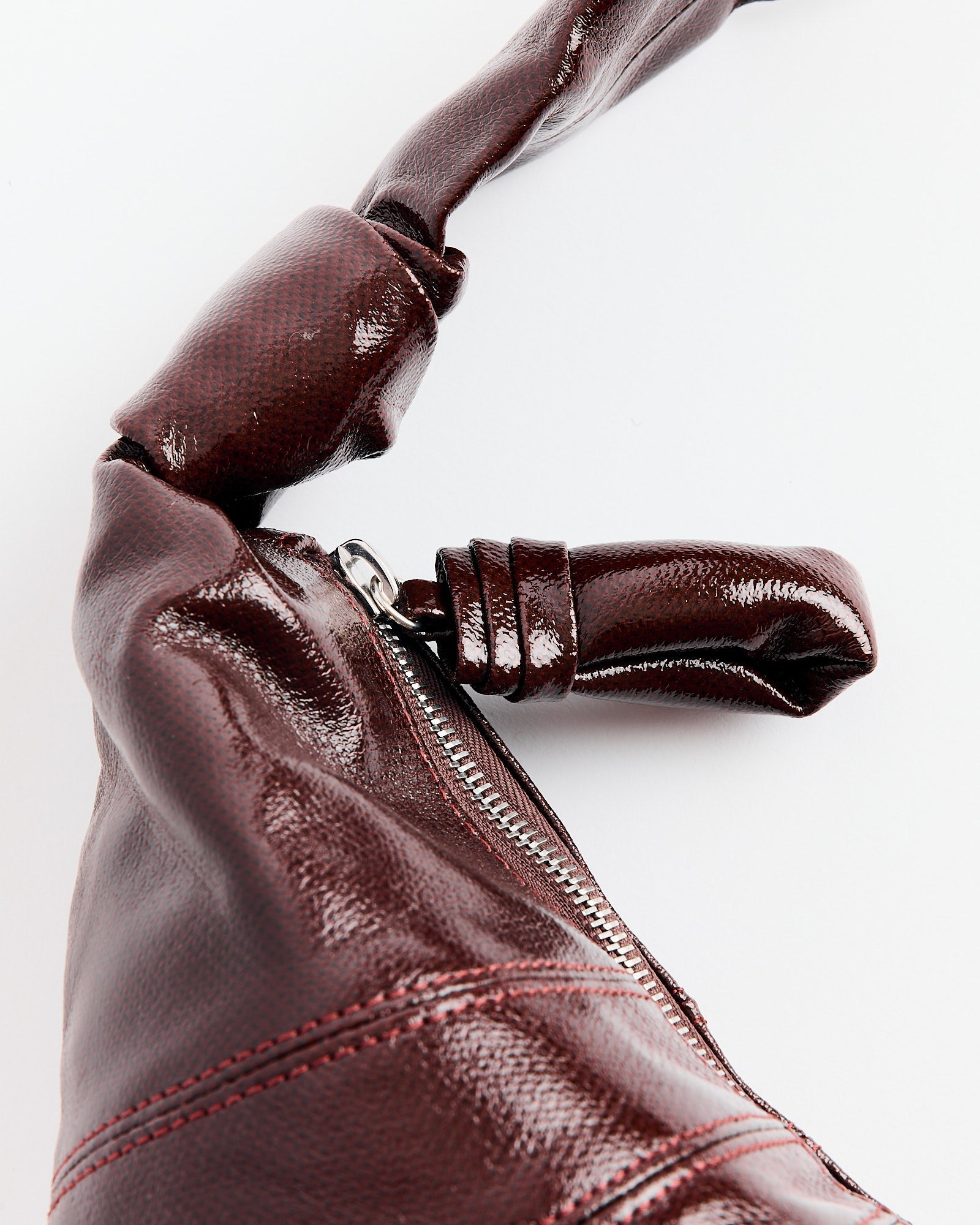 A close-up of the Lemaire Small Croissant Bag in Chocolate Fondant, featuring a silver zipper and twisted handle detail, set against a plain white background.