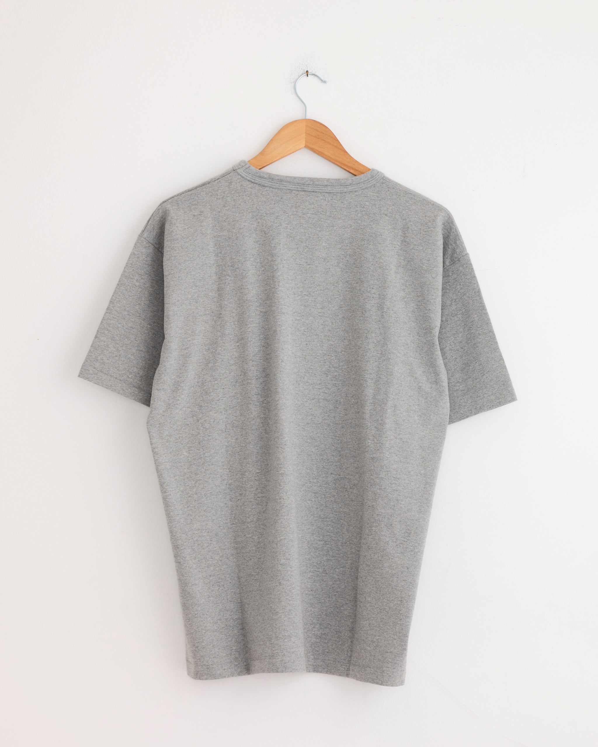 The Sunray Makaha Japanese Jersey T-Shirt in Hambledon Grey is displayed on a wooden hanger against a white wall, with the back view visible.