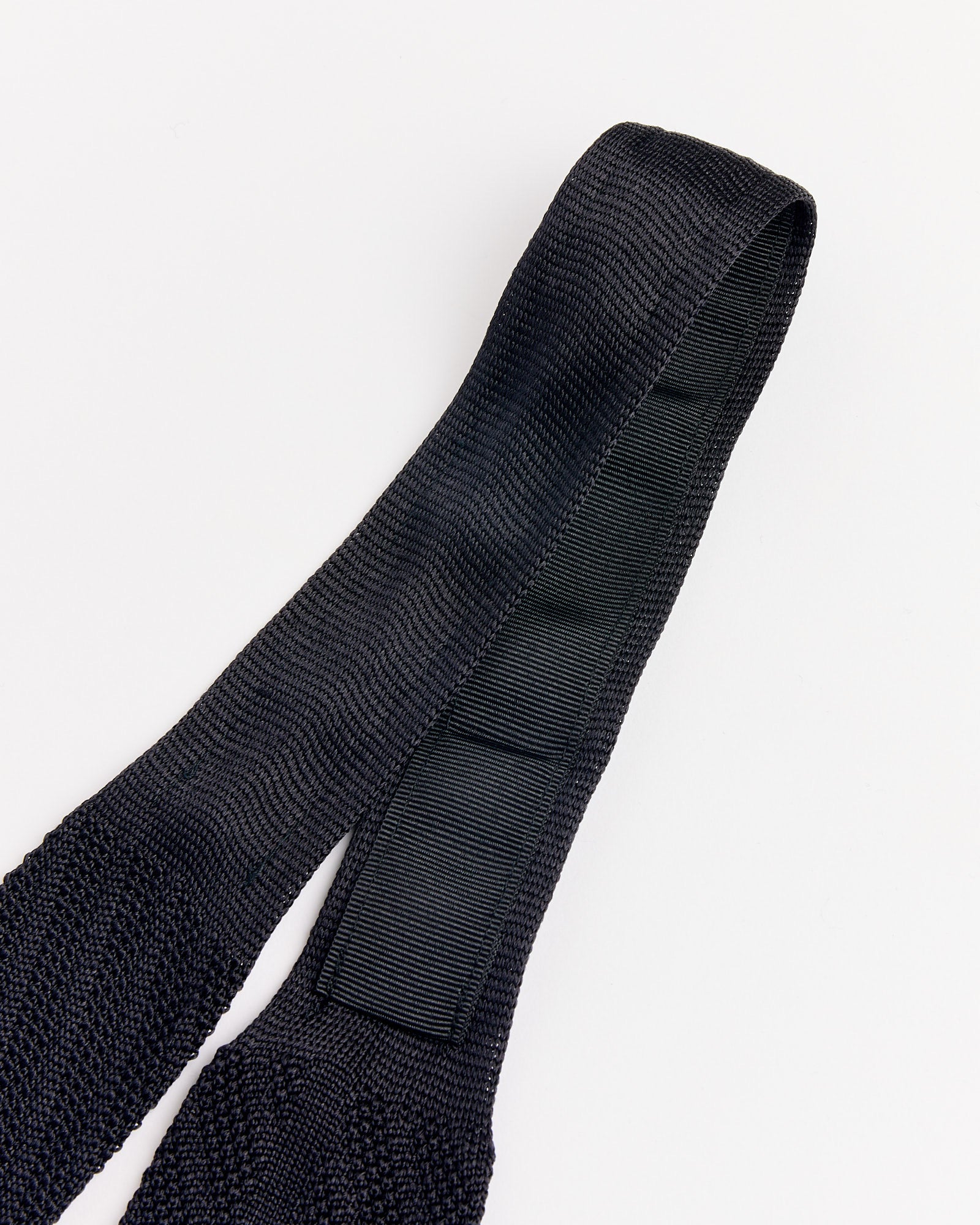 Close-up of the mfpen Formal Tie in Black Knitted Stripe, featuring a refined textured knit, smooth reinforced section, and looped end, all shown against a plain white background.