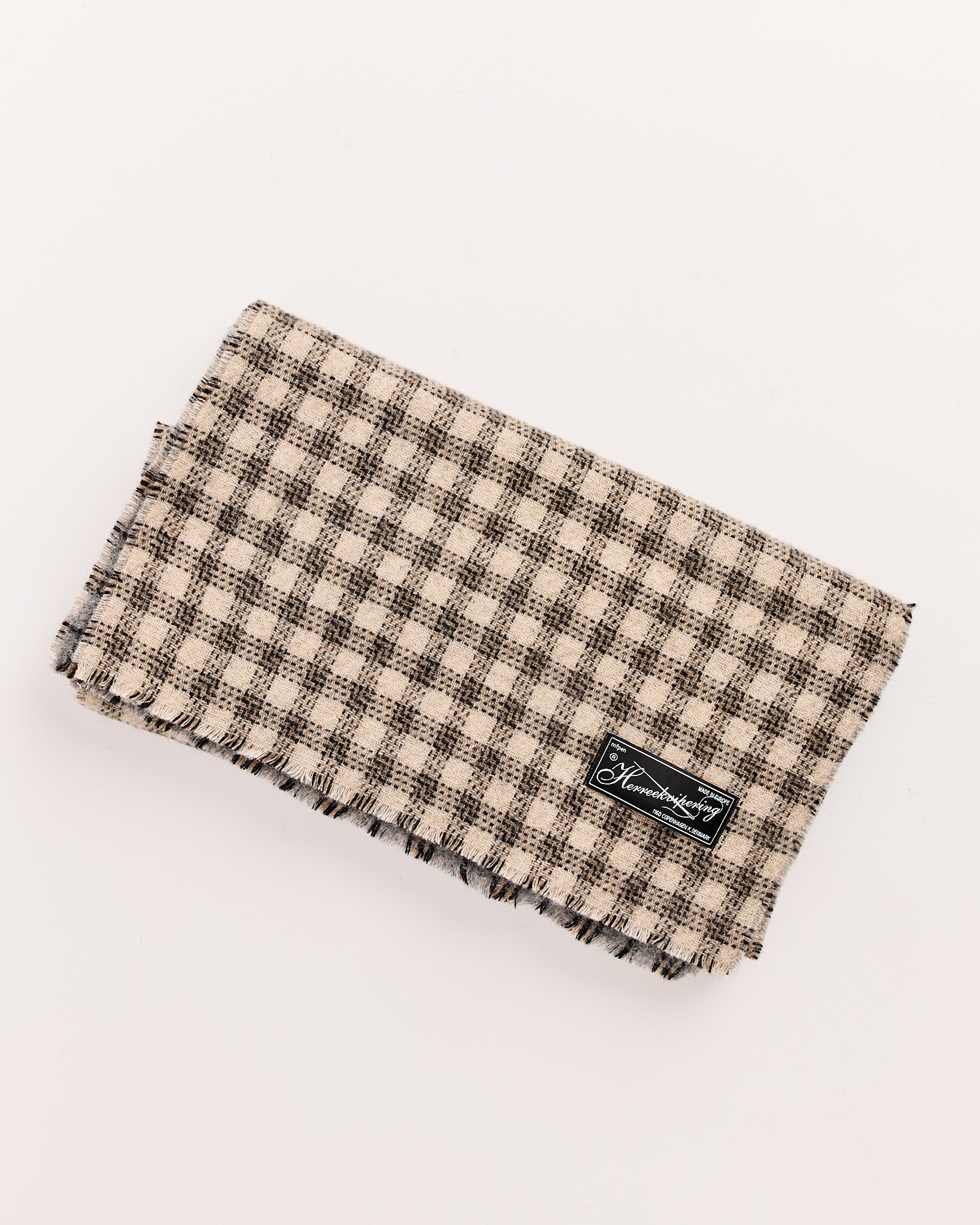 Mfpen Wool Scarf in Grey Double Faced Check, made in Italy, features a folded jacquard check design with frayed edges and a black fabric label on one corner, displayed on a white background.
