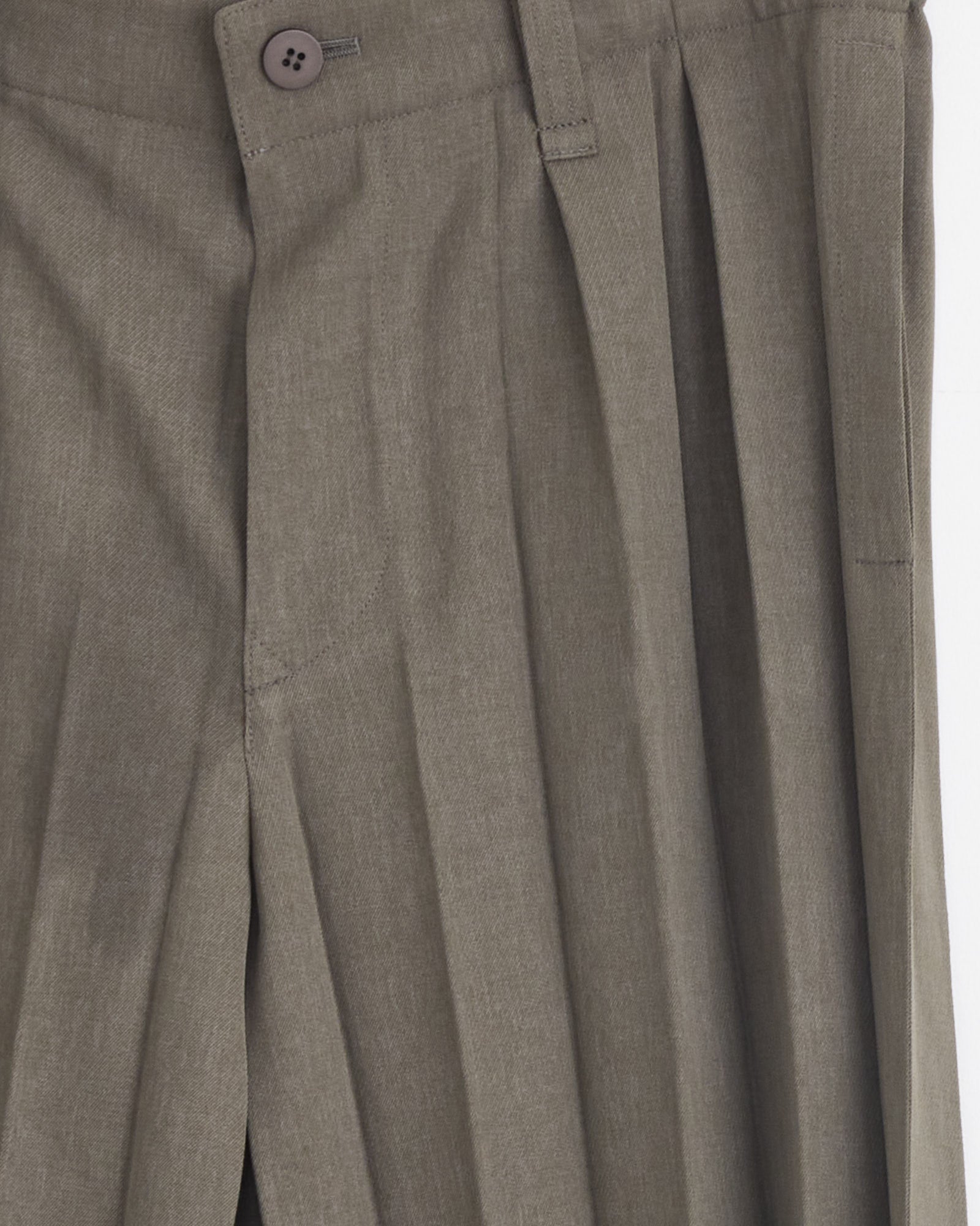 Close-up of the Edge Ensemble Pant in Khaki by Homme Plissé Issey Miyake, featuring accordion pleats, button closure, belt loops, and front creases. The lightweight fabric has a subtle texture inspired by signature Plissé designs.