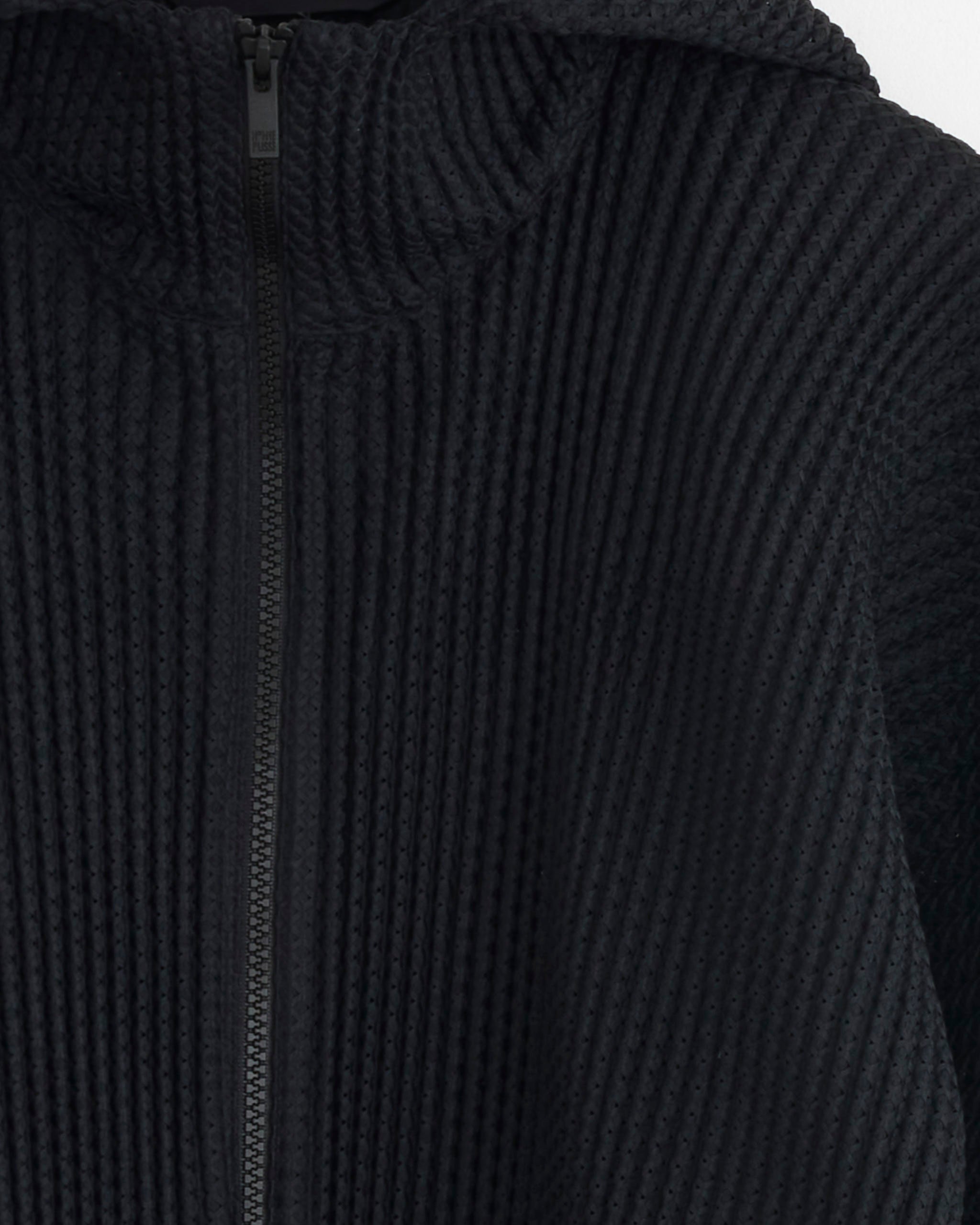 Close-up of the Wickerwork Mesh Jacket in Black by Homme Plissé Issey Miyake, featuring a textured, ribbed design with a front zipper and hood detail.