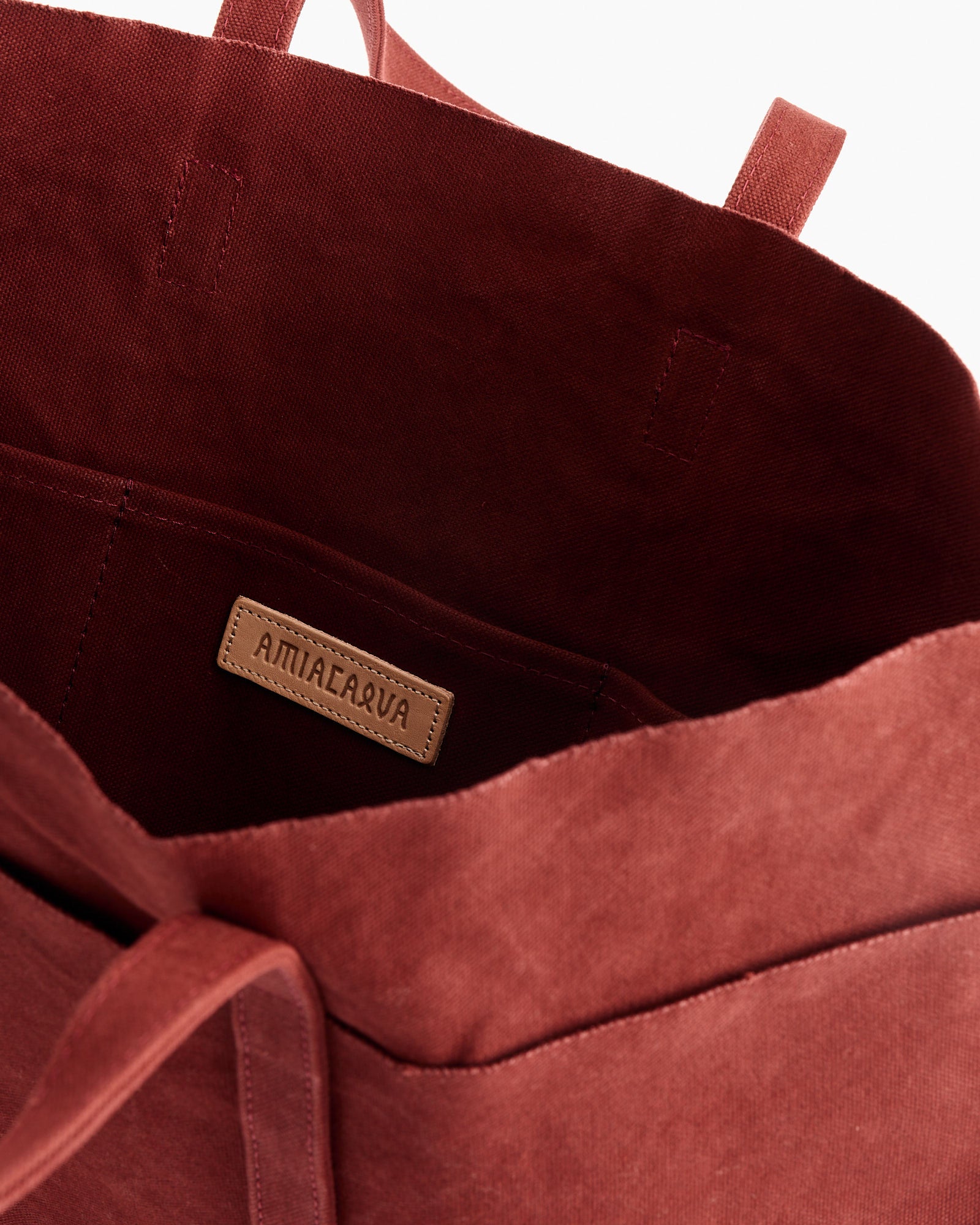 Close-up of an open Amiacalva Washed Canvas 6 Pockets Medium Tote in Burgundy, featuring visible stitched inner pockets and a brown leather label. This sturdy cotton canvas tote is both stylish and practical for everyday use.