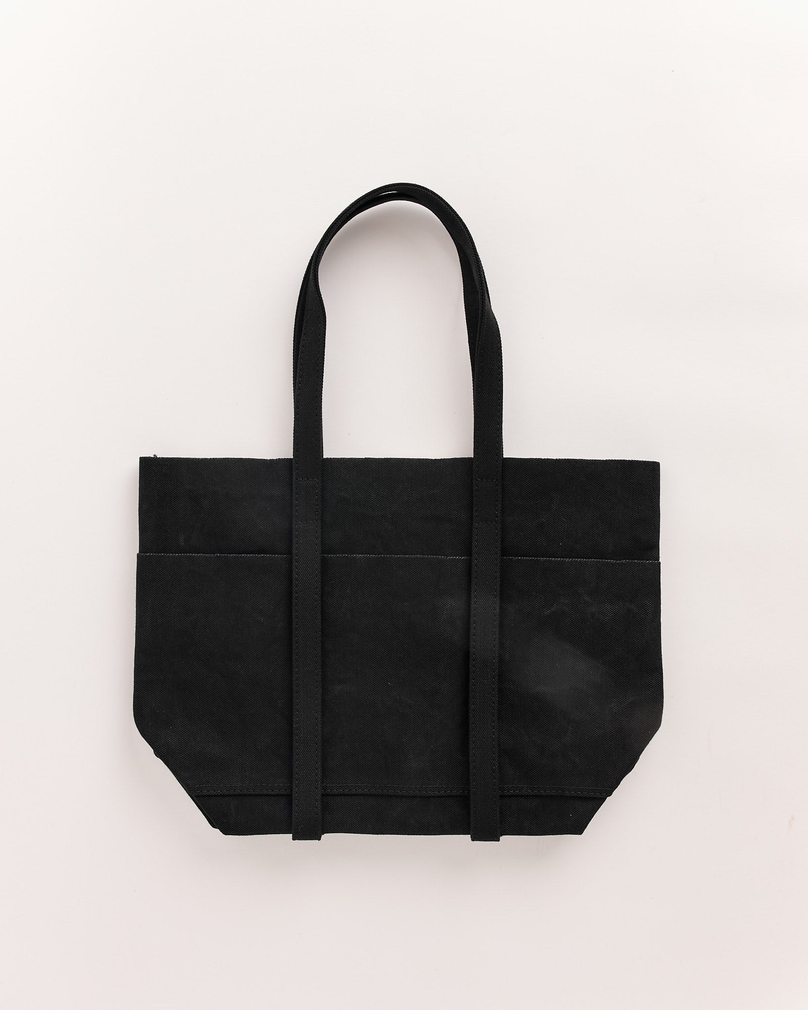 The Amiacalva Washed Canvas 6 Pockets Small Tote in Black, made in Japan, features two long handles, visible stitching, and a minimalist logo-free design. It's shown laid flat on a light neutral background.