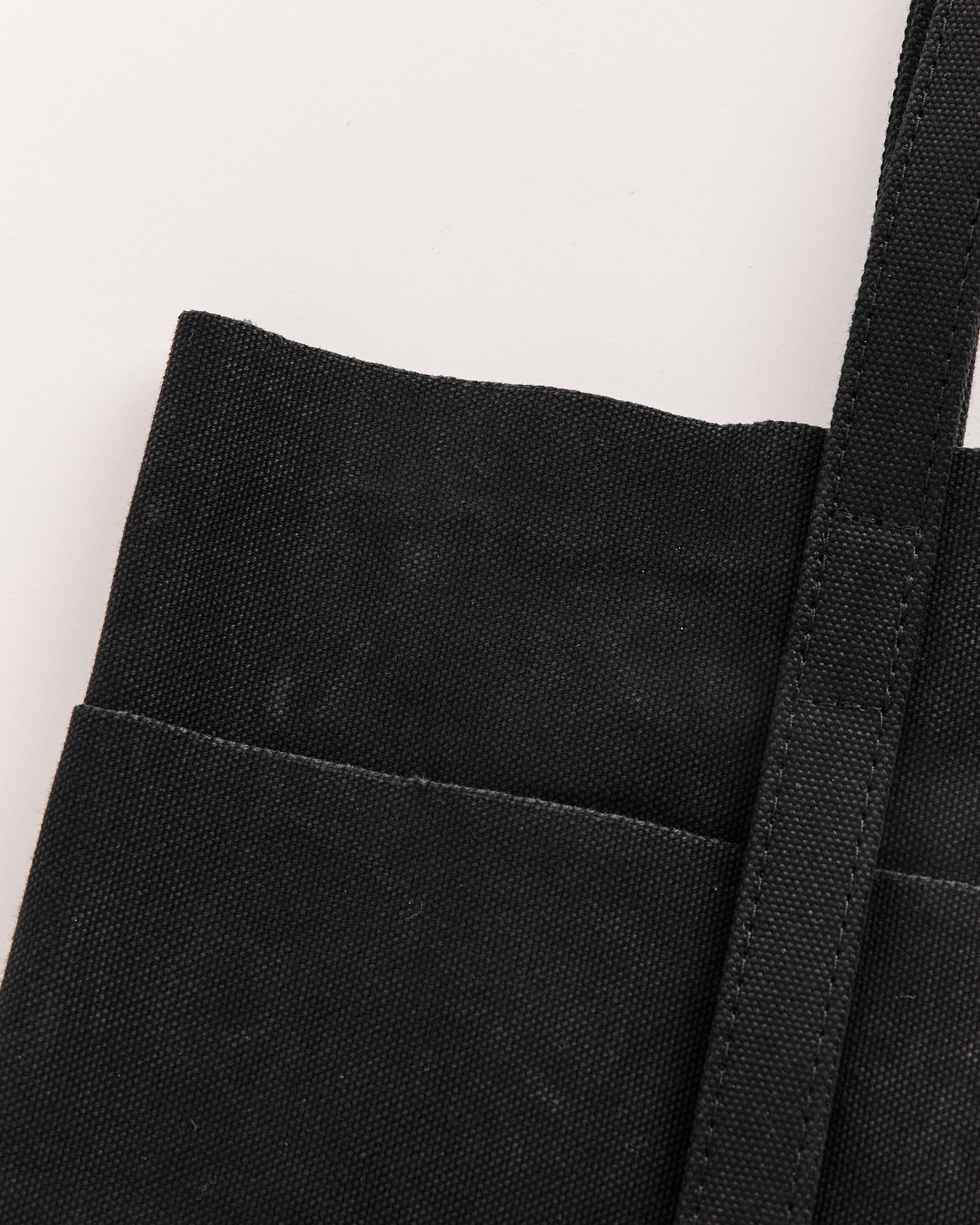 Close-up of the Amiacalva Washed Canvas 6 Pockets Small Tote in Black, made in Japan, featuring visible stitching and a shoulder strap against a light background.