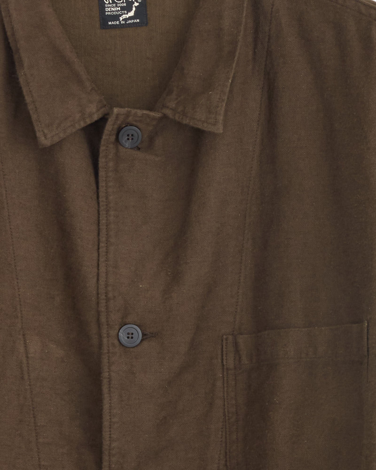 Close-up of the orSlow Relax Fit Simple Work Jacket in Coffee Brown, featuring a collar, front pocket, and two black buttons. The soft cotton-linen moleskin fabric highlights its quality craftsmanship. Shirt label shows "made in Japan" at top.