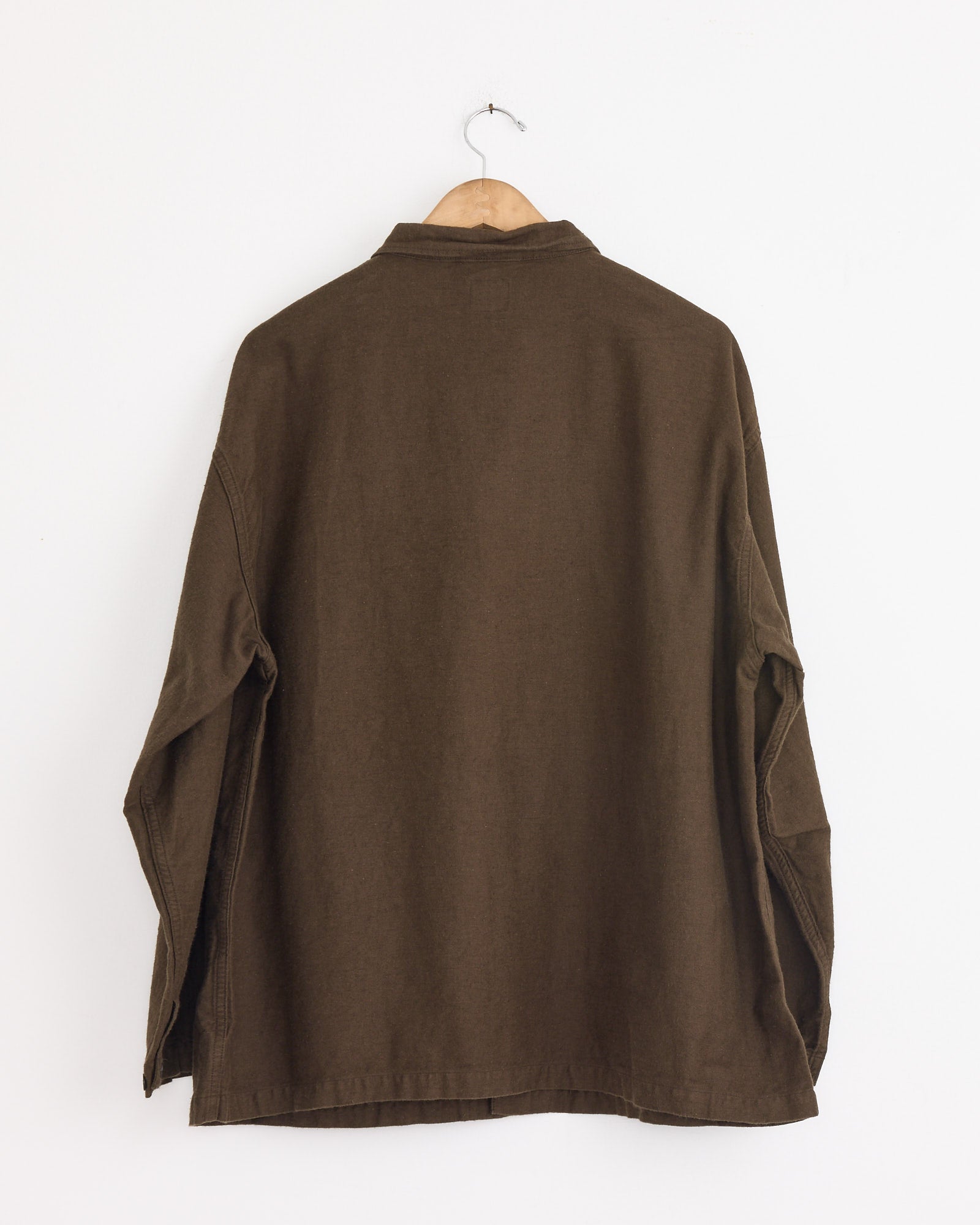 The orSlow Relax Fit Simple Work Jacket in Coffee Brown, crafted from cotton-linen moleskin, hangs on a wooden hanger against a plain white wall, displayed from the back.