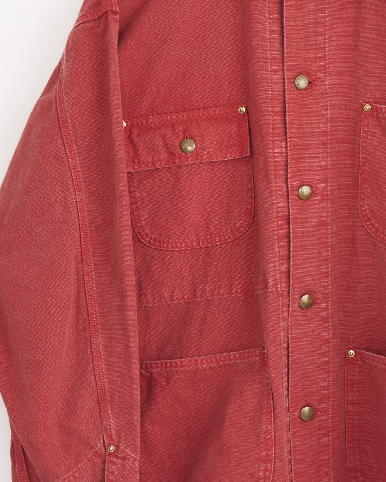 Close-up of the orSlow Relax Fit Oxford Coverall in Red, featuring gold snap buttons and multiple front pockets, highlighting the upper left side and sleeve.