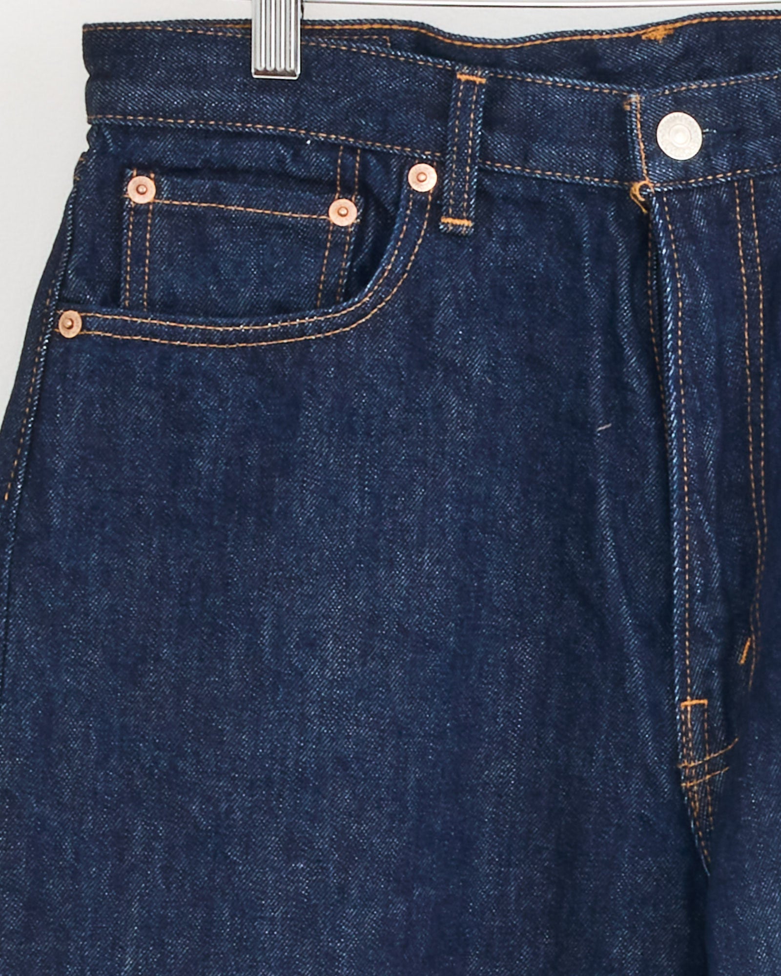 Close-up of the orSlow 101 Dad's Fit Denim Pant in One Wash, featuring relaxed fit dark blue Japanese denim with orange stitching, a metal button, and copper rivets on the front pockets.