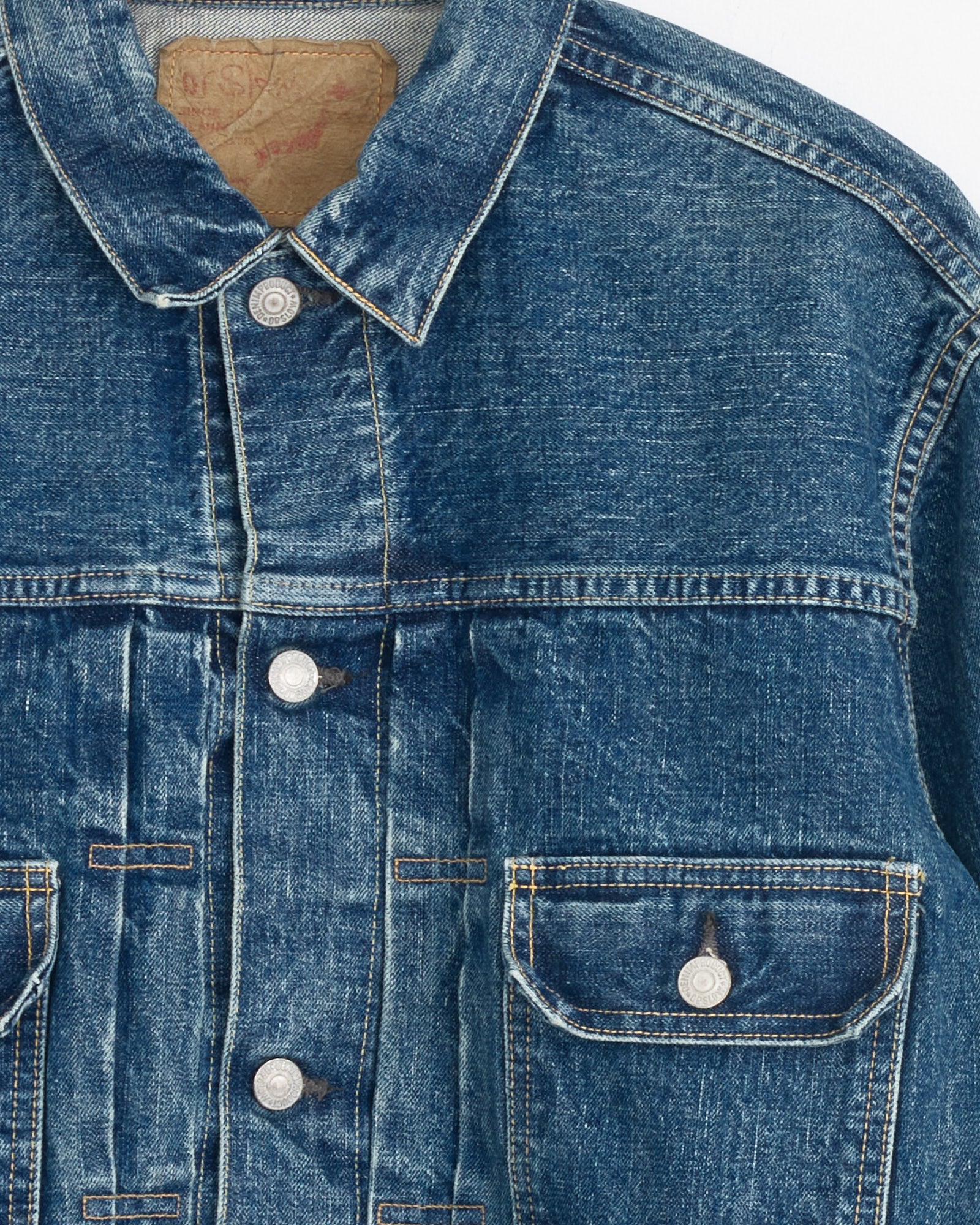 Close-up of the upper front of the orSlow Type 2 1950’s Denim Jacket in 2 Year Wash, featuring silver buttons, a buttoned chest pocket, visible seams, and part of a brown leather label at the collar.