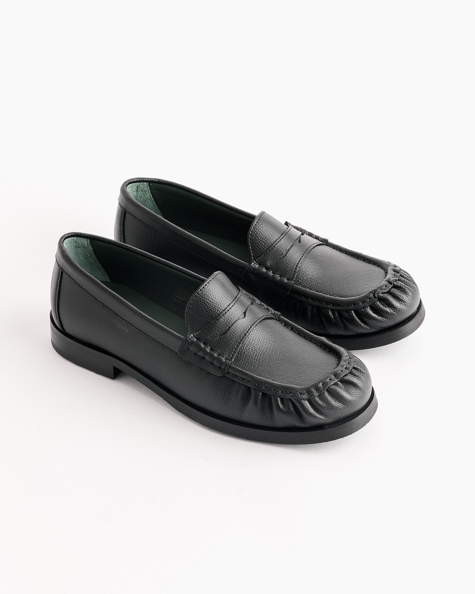 The Ogee Loafer in Black by Vinny's is a pair of black leather loafers with a ruffled toe box, visible stitching, and textured detailing around the toe, displayed on a plain white background.