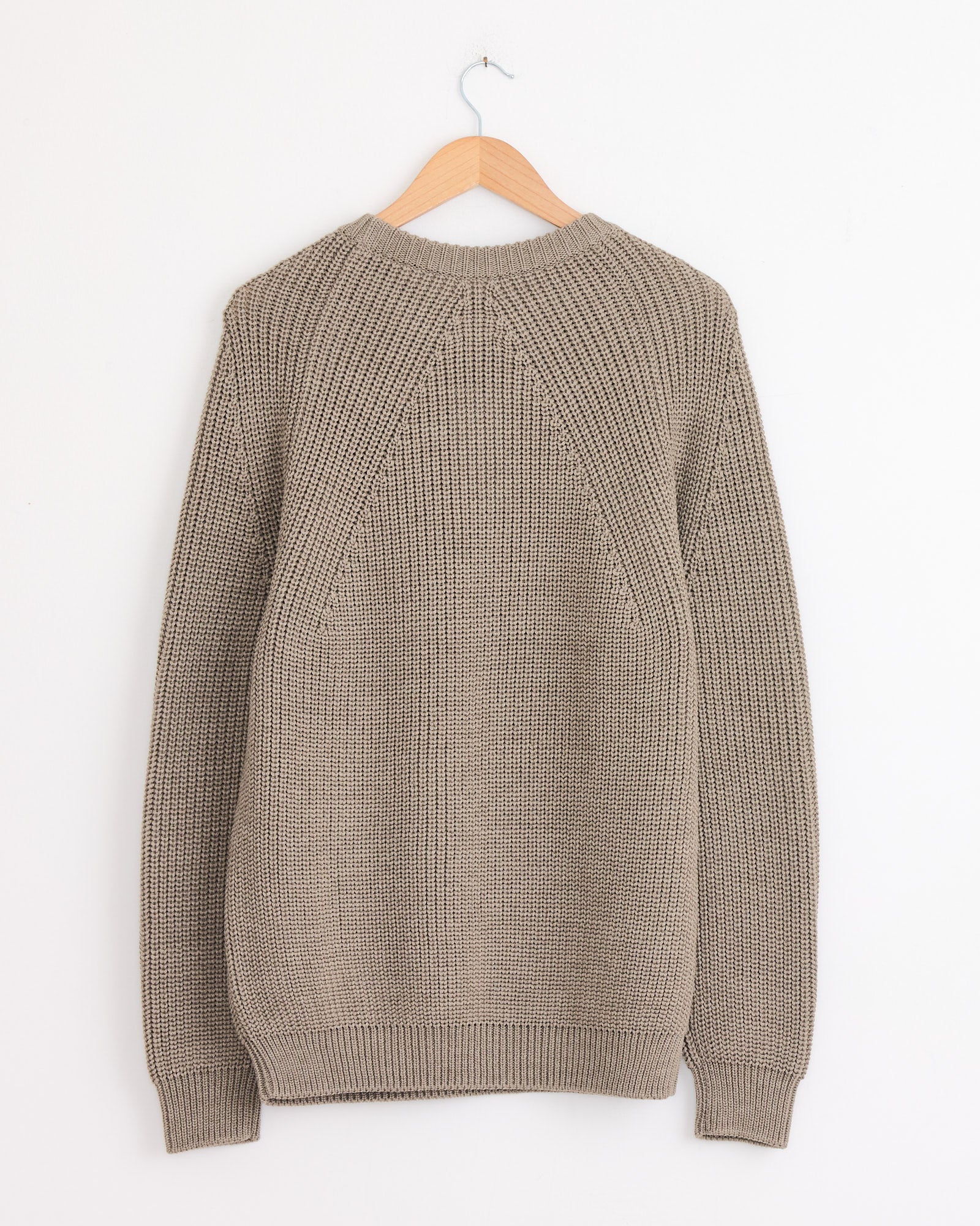 A Batoner Signature Crewneck in Merange Brown hangs on a wooden hanger against a plain white wall, displayed with the back facing forward.