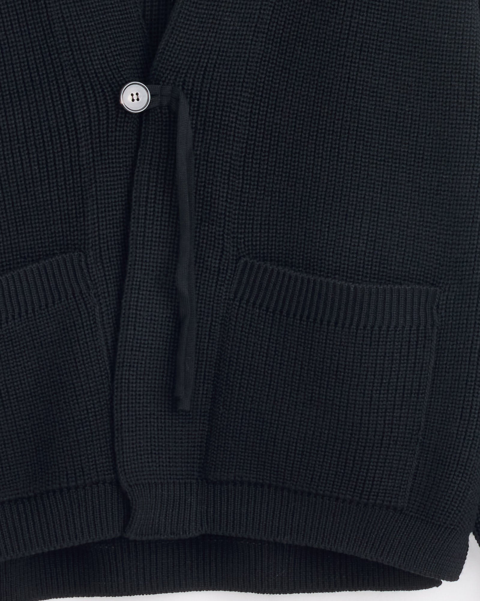 Close-up of the Batoner Waso 1 Button Cardigan in Black, crafted in Japan from premium SOLIDWOOL yarn with two front patch pockets, a visible button, and ribbed hems.