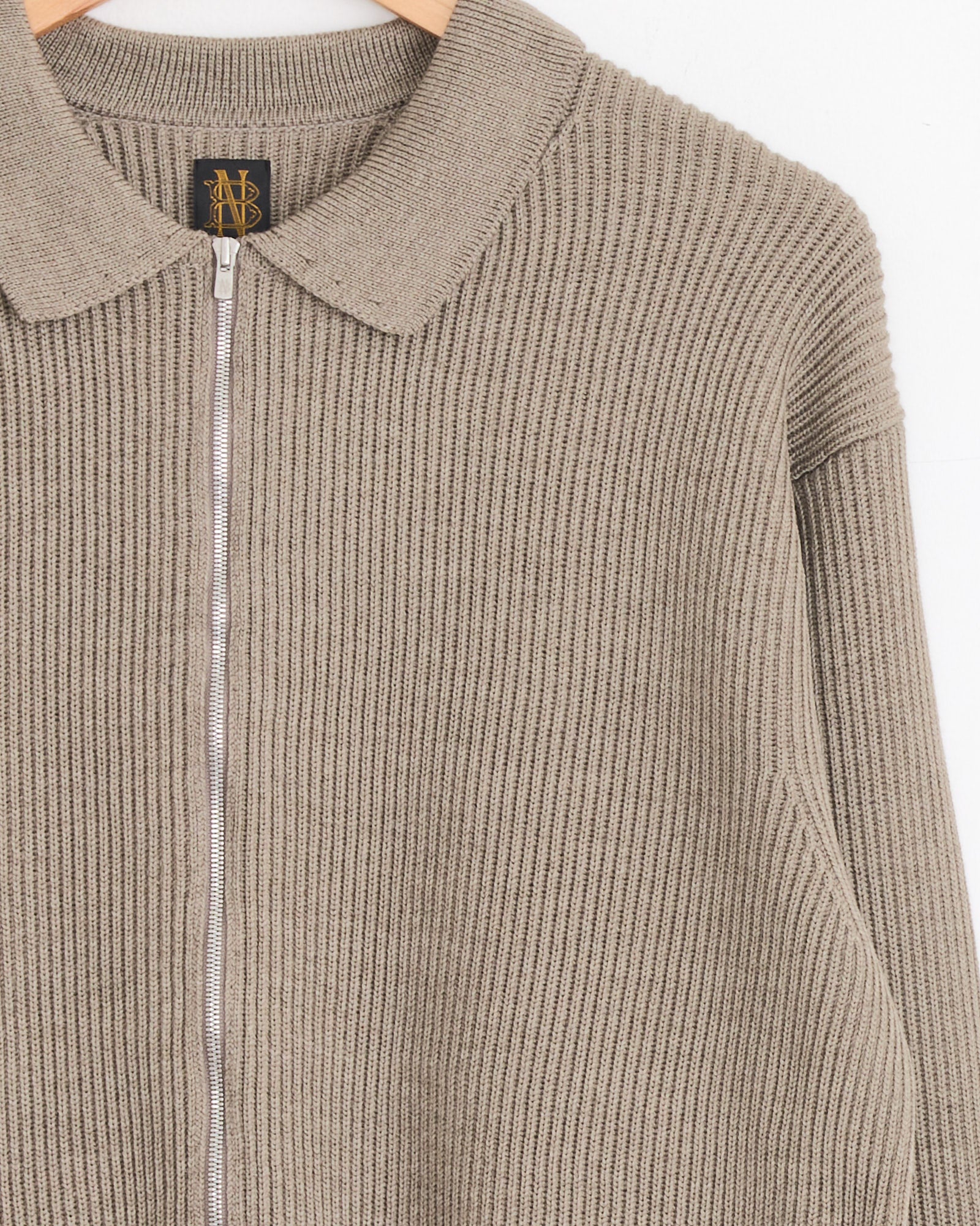 A close-up of a Batoner Zip Up cardigan in Merange Brown, featuring a collar, made in Japan, hanging on a wooden hanger against a plain white background.