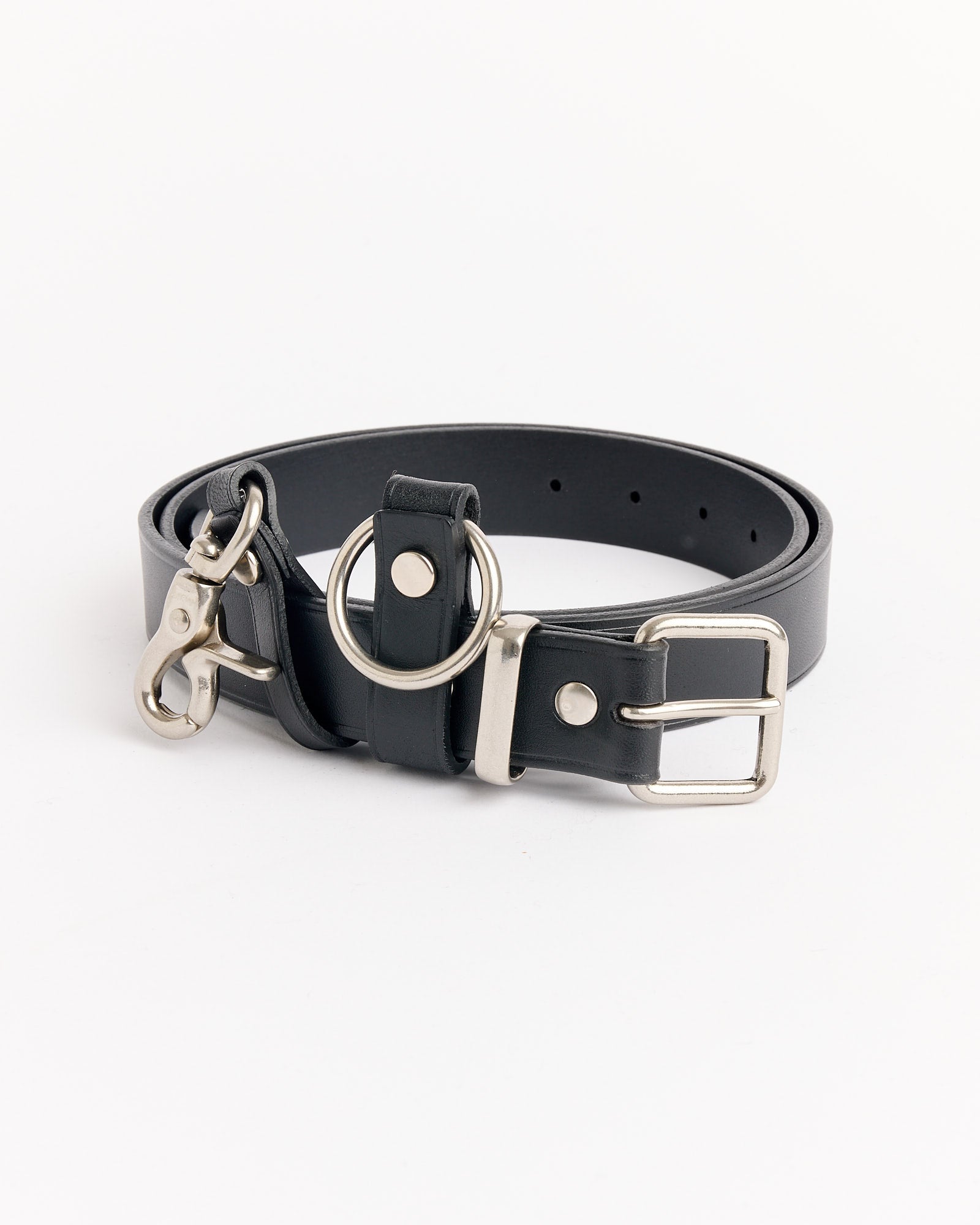 The 301 Belt in Black by Comme Des Garçons Homme features black leather with a silver buckle, metal ring, and clasp, coiled neatly on a white background. For fit or sizing questions, contact our online chat support.